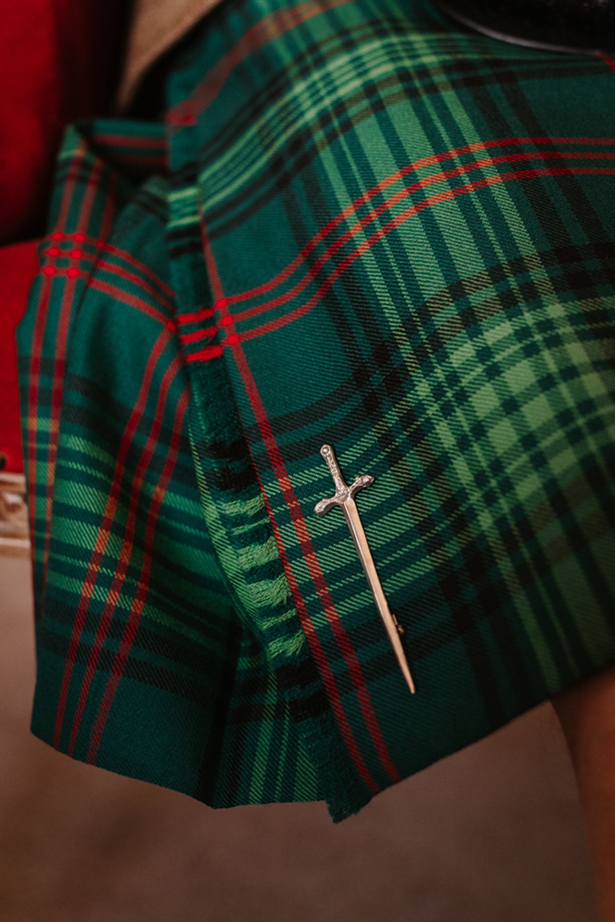 Green tartan kilt fastened with a silver sword-shaped brooch.