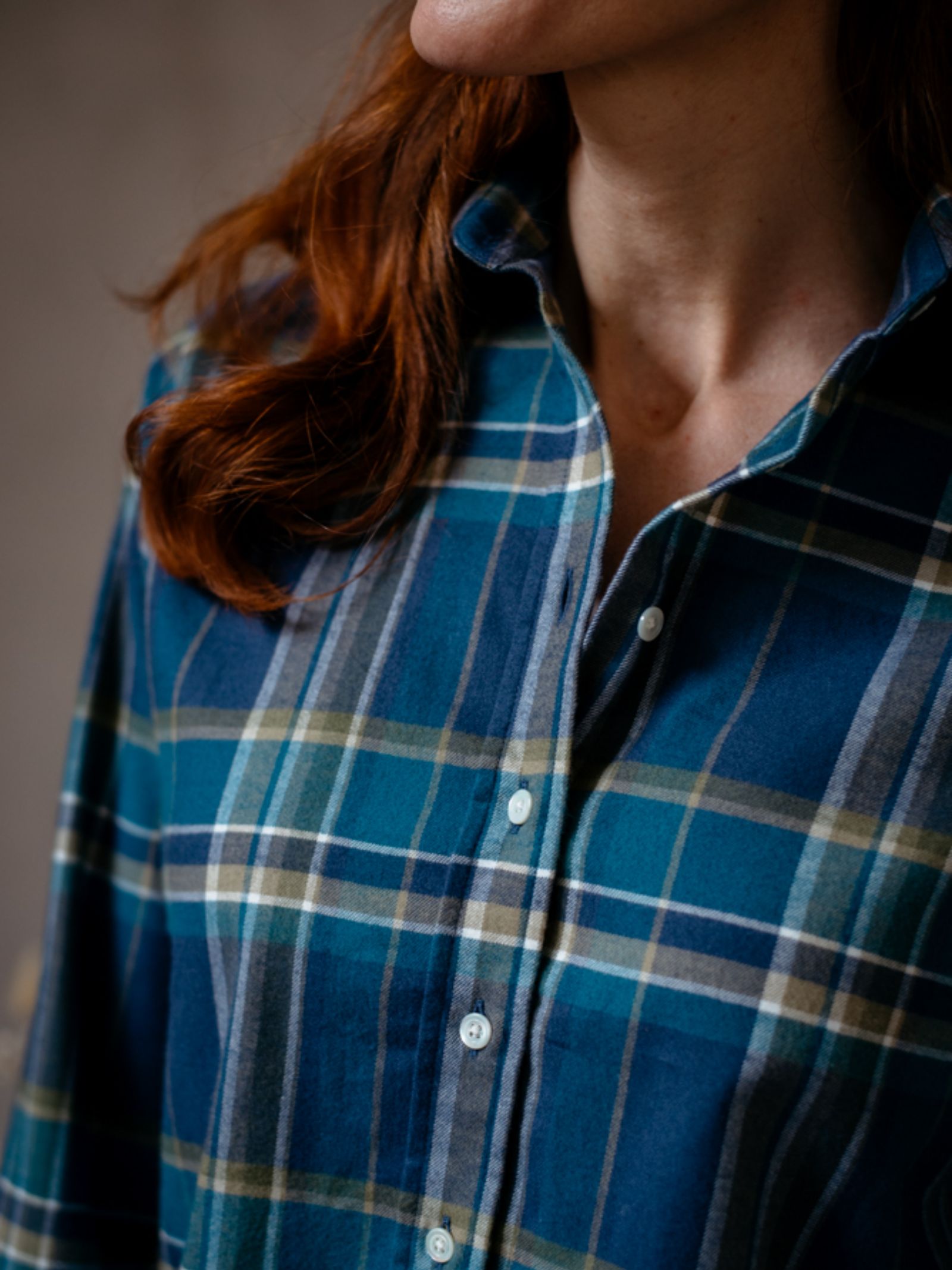 A person with long red hair wears the Campbells of Beauly Brushed Cotton Shirt in a blue, green, and white plaid; only their lower face, neck, and upper torso are visible. The shirt features a classic fit and soft brushed cotton for comfort.