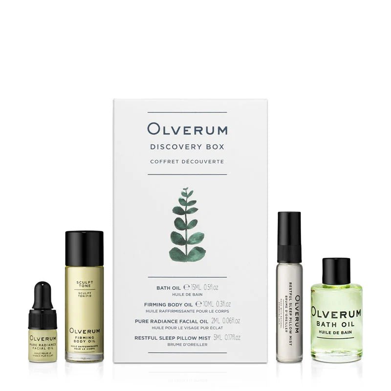 OLVERUM Discovery Box with Bath Oil, Firming Body Oil, facial oil, and Restful Sleep Pillow Mist is arranged around a white box adorned with a green leaf illustration on the front.