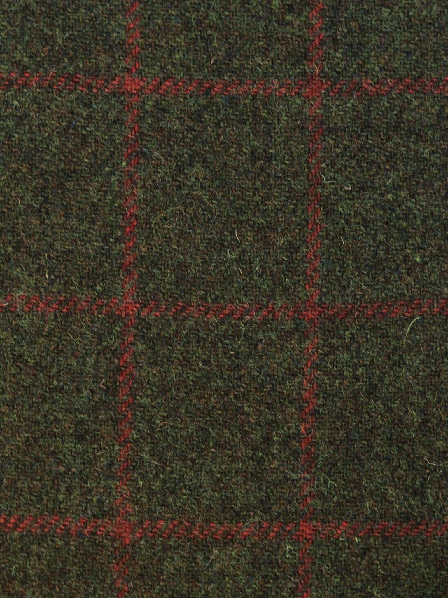 A close-up of House Tweed 93907 by Campbell's of Beauly shows dark green fabric with intersecting red check lines, highlighting the rich texture and classic woven pattern.