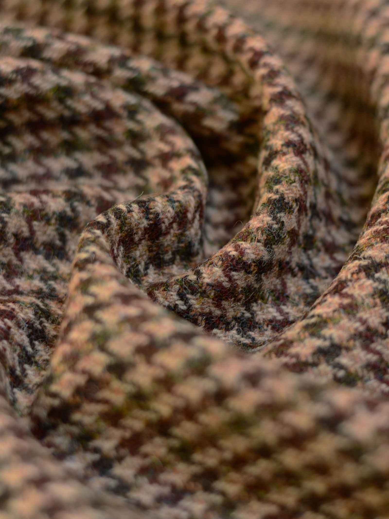 Close-up of House Tweed 93904 by Campbell's of Beauly: brown, tan, and green houndstooth patterned wool fabric with soft folds and intricate Scottish weaving for a cozy look.