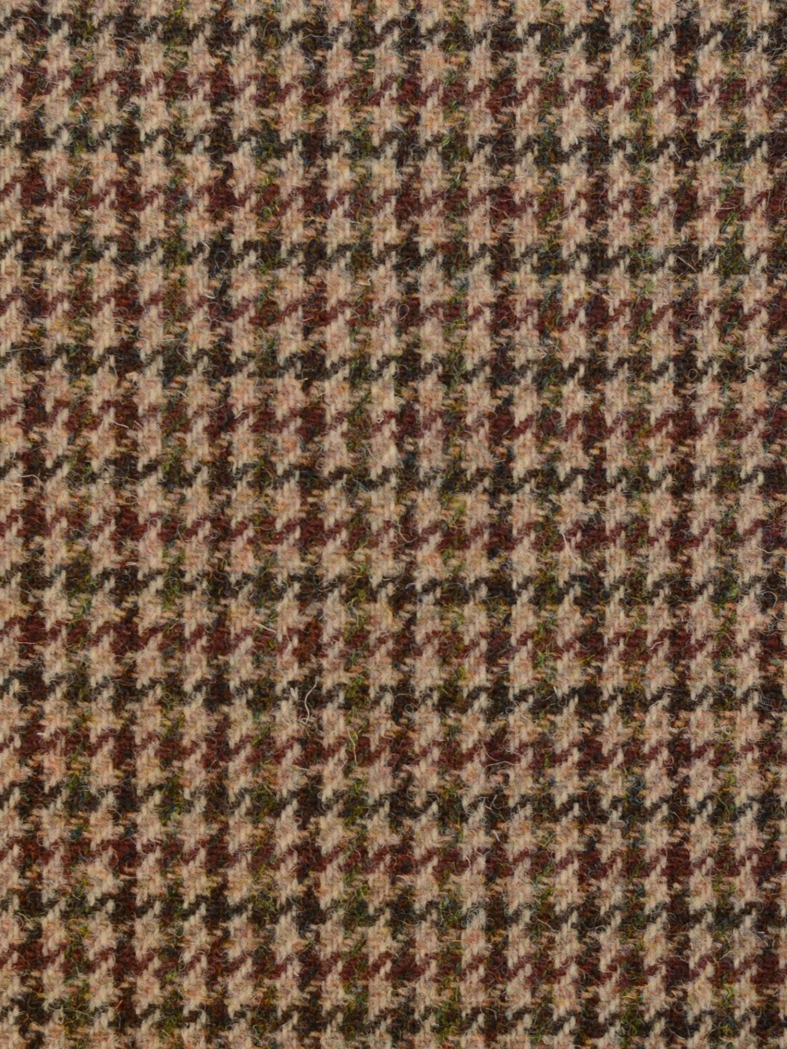 Close-up of House Tweed 93904 by Campbell's of Beauly, featuring a houndstooth pattern in brown, beige, green, and black. The repeating jagged shapes evoke classic Scottish weaving and add rich texture.