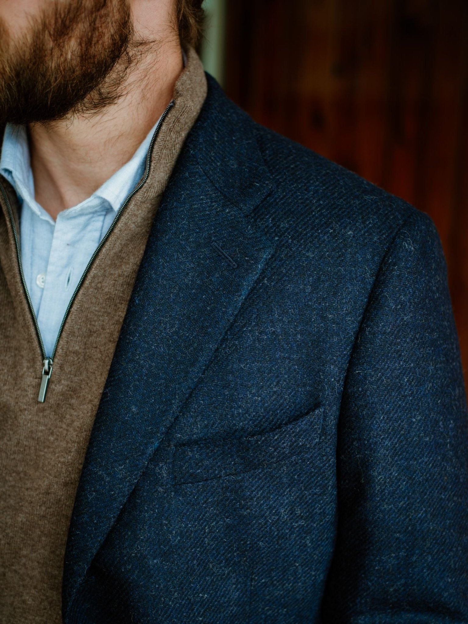 A man with a beard wearing the Campbells of Beauly Navy Twill House Jacket over a brown zip-up sweater and light blue collared shirt, shown from the shoulders up.