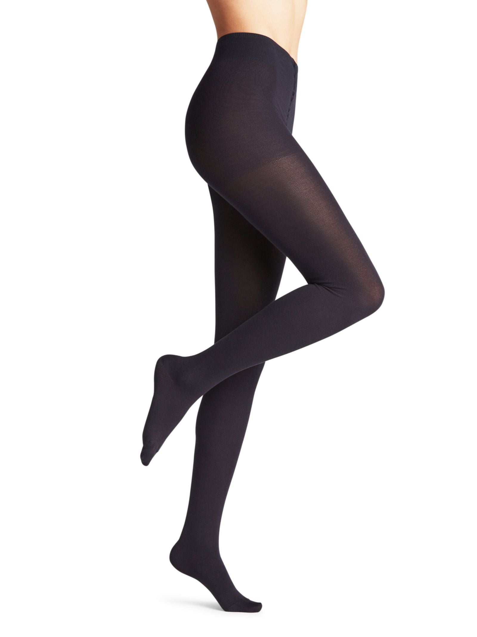 A person in FALKE Cotton Tights made from sustainable cotton stands on one leg with the other bent at the knee, shown from midriff to feet against a plain white backdrop.