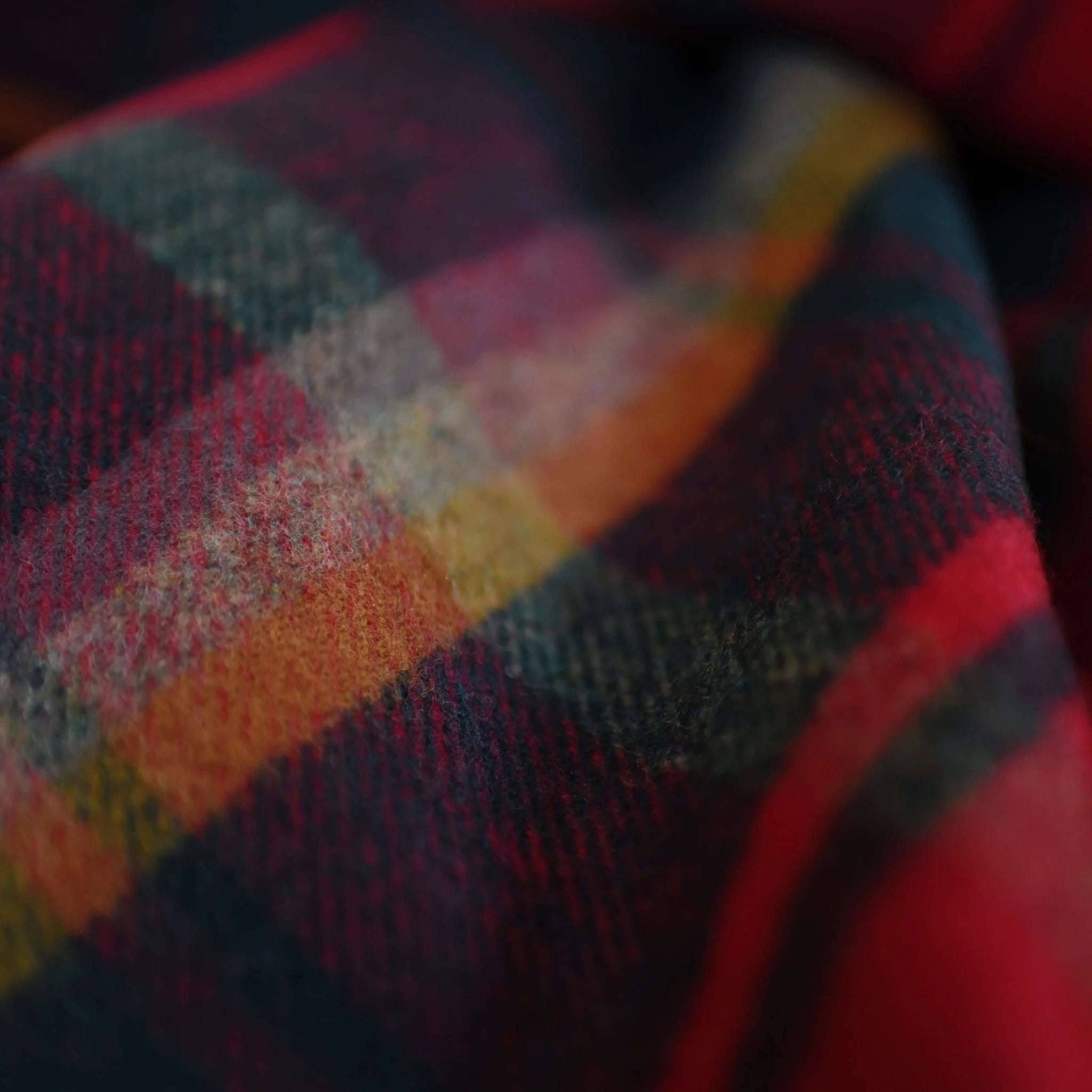 A close-up of Campbell's of Beauly Auld Stock Lambswool Blanket shows its soft, woven texture and classic tartan plaid in red, yellow, blue, and green.