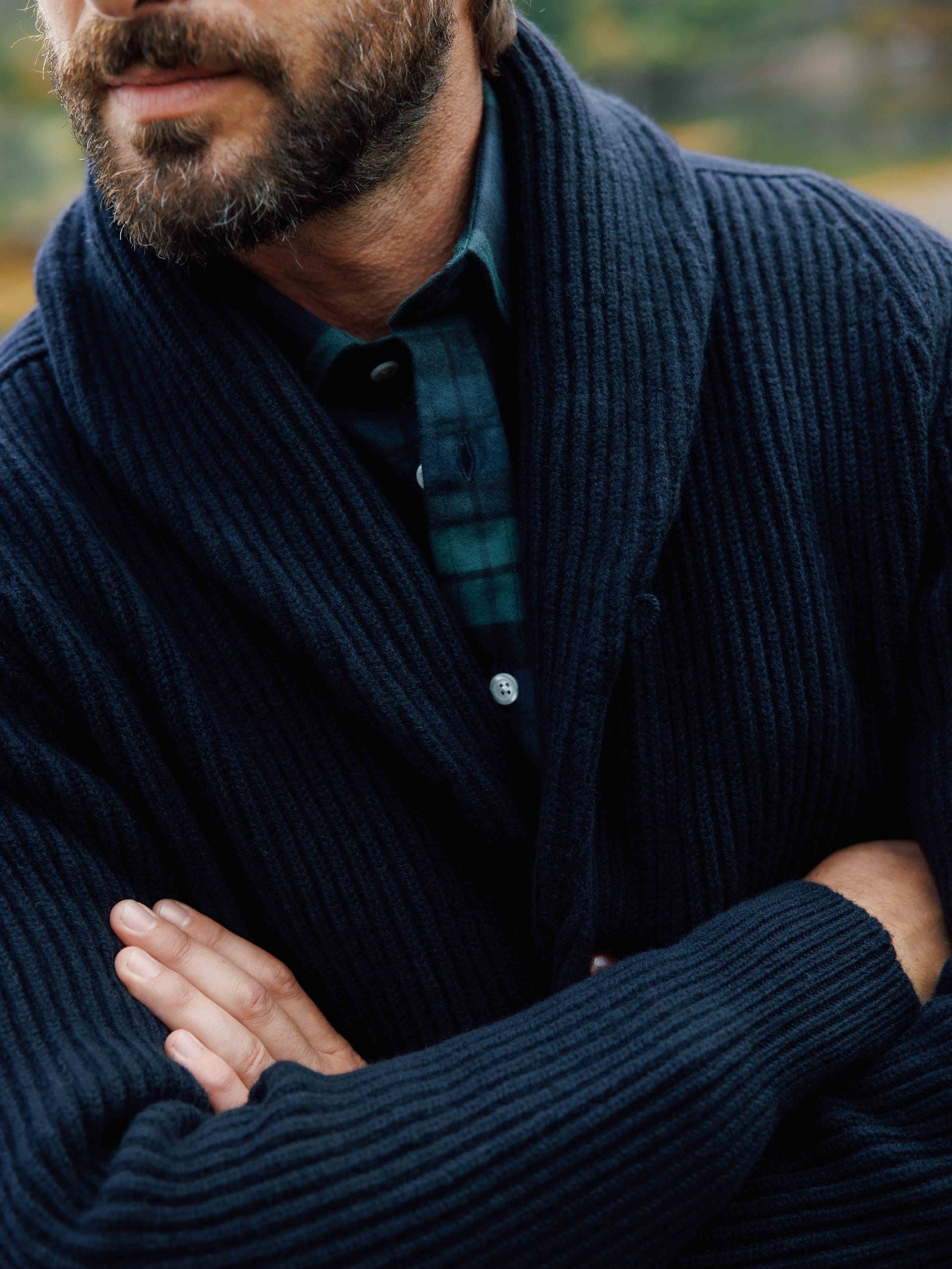 A bearded man with folded arms wears a Campbell's of Beauly Tartan Shirt under a navy blue ribbed cardigan. Only his lower face and torso are visible.