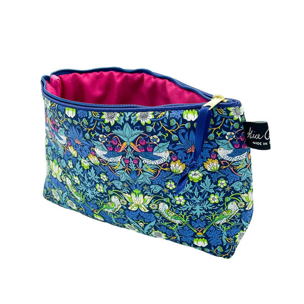The Alice Caroline Liberty Print Cosmetic Bag features a blue zippered design with a floral and bird print and bright pink lining, finished with a small branded side tag.