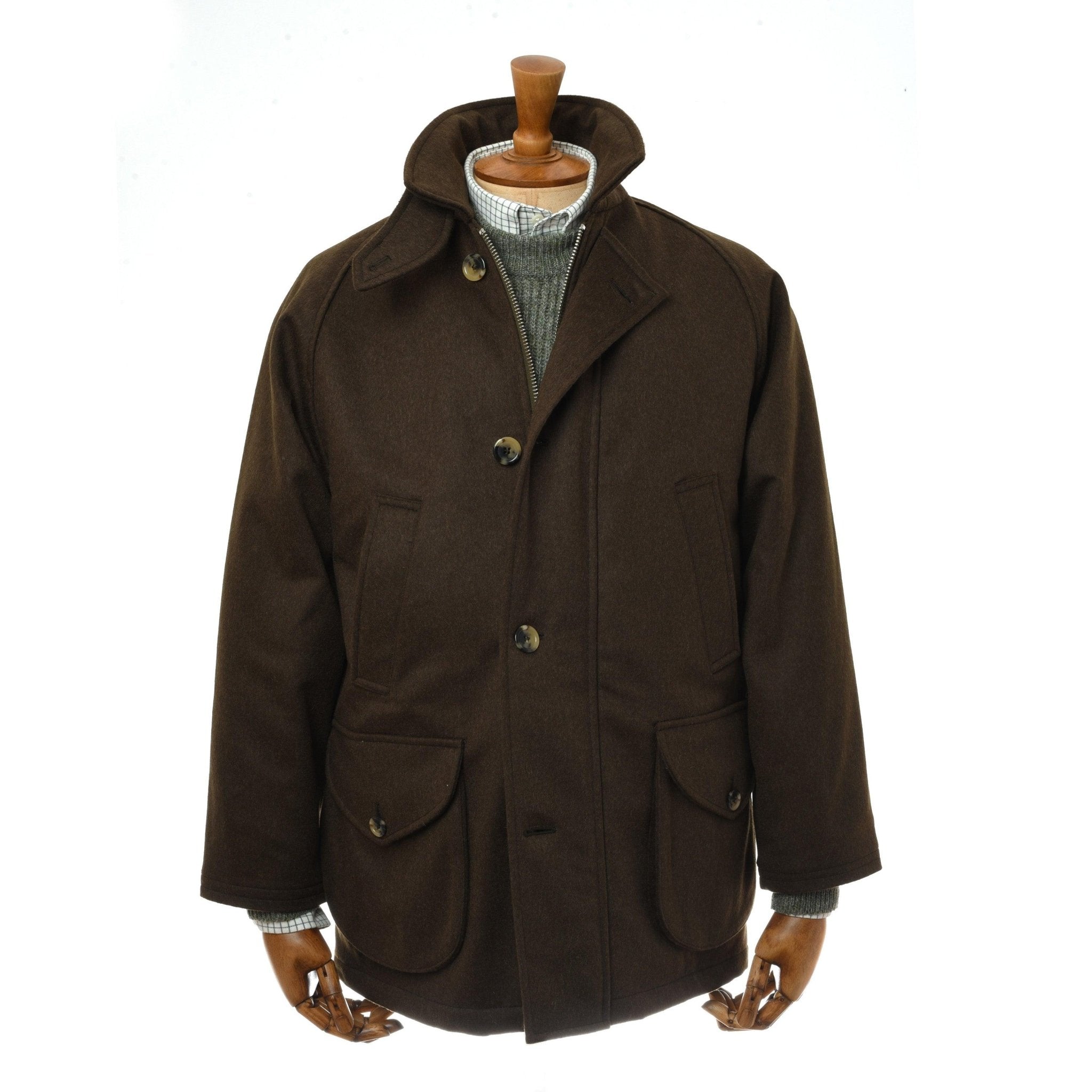 The Cannich Coat by Campbells of Beauly, shown in Loden Green Austrian wool on a mannequin, features a high storm collar, button closure, two large front flap pockets, and a light gray sweater visible underneath.