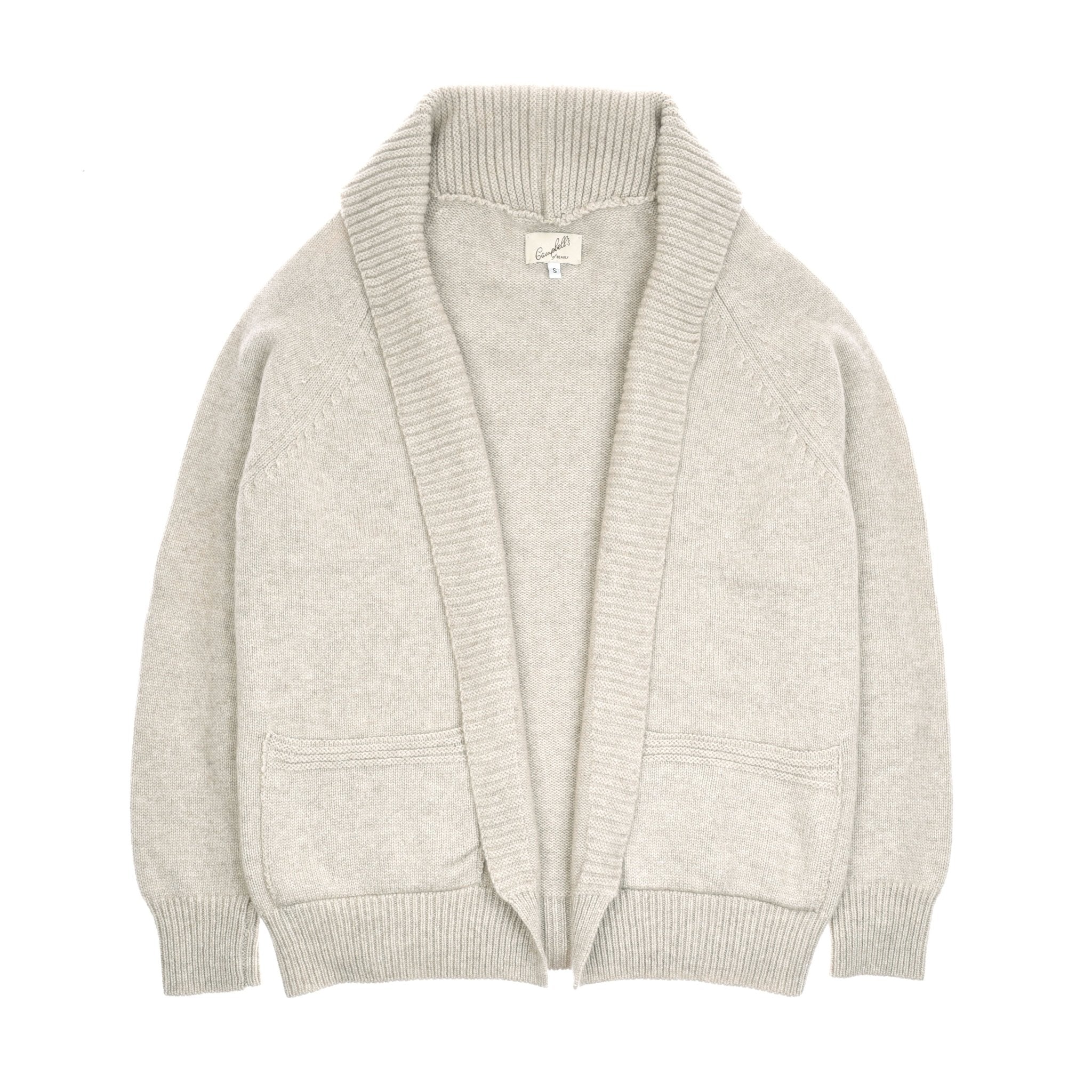 The Cashmere Shawl Cardigan by Campbells of Beauly features light gray cashmere, long sleeves, open front, ribbed cuffs and hem, wide shawl collar, two front pockets, and a visible neck tag. Shown laid flat on a white background.