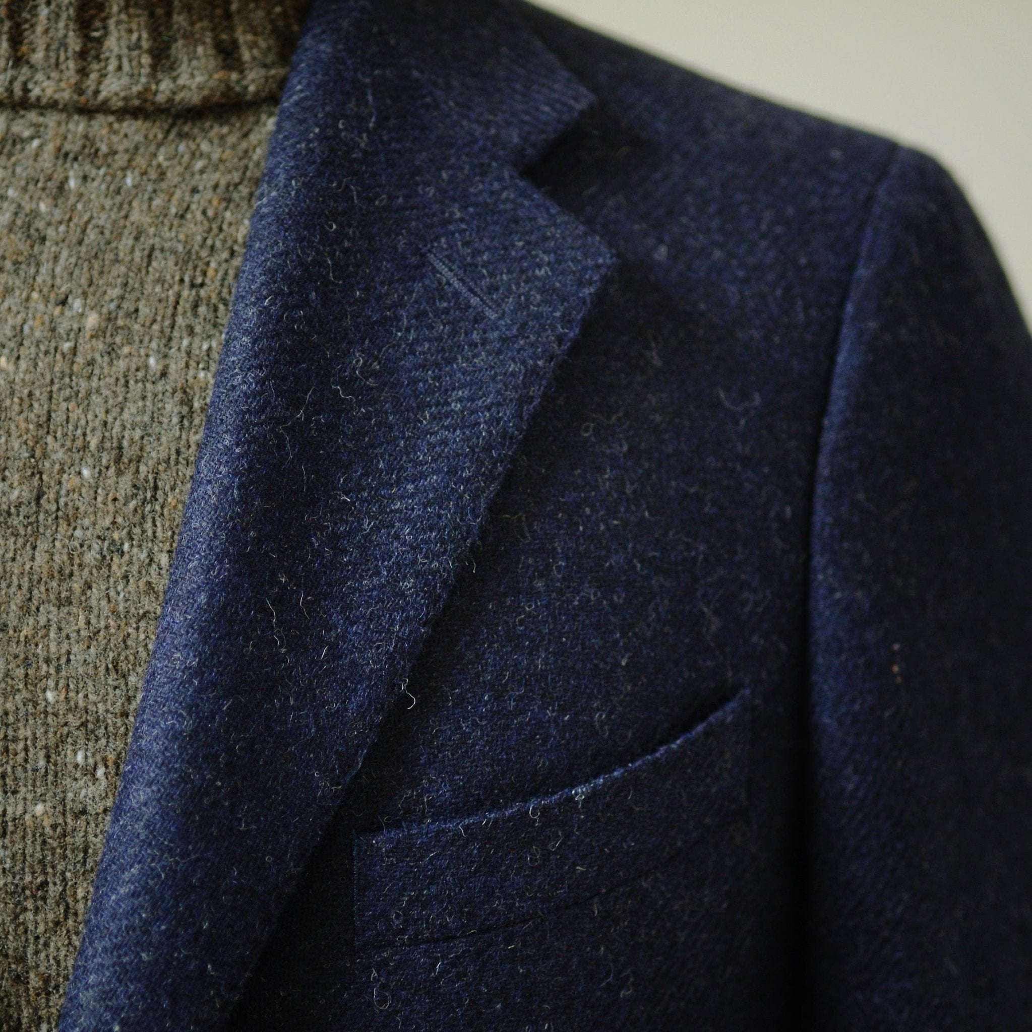 Close-up of a person wearing the Campbells of Beauly Navy Twill House Jacket over a brown knit turtleneck. Only the upper chest and collar are visible.
