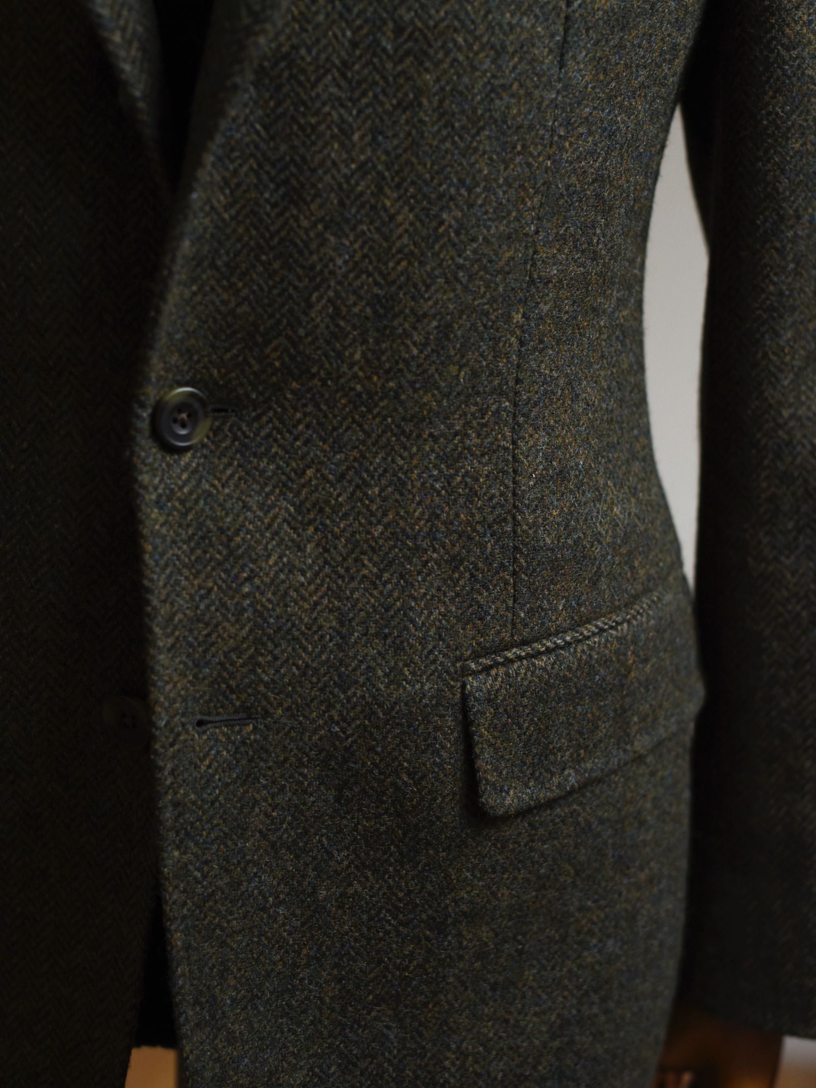 Close-up of the Campbells of Beauly Green Herringbone House Jacket in Shetland wool, highlighting its buttons, flap pocket, and the rich texture of its tweed fabric.