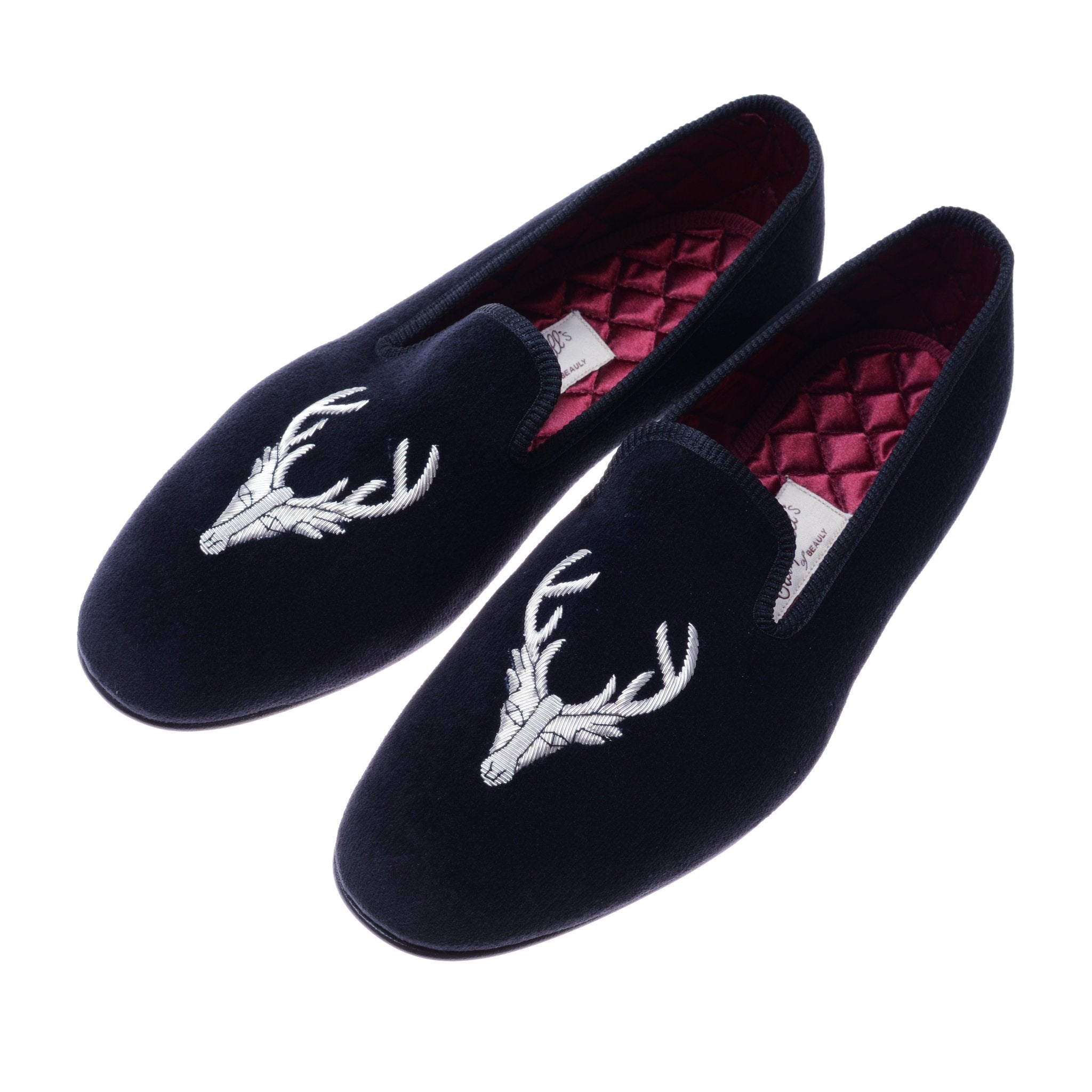 A pair of Navy Stag Velvet Slippers by Campbells of Beauly, featuring an embroidered stag motif on the toes and quilted maroon linings—perfect for refined evening wear.