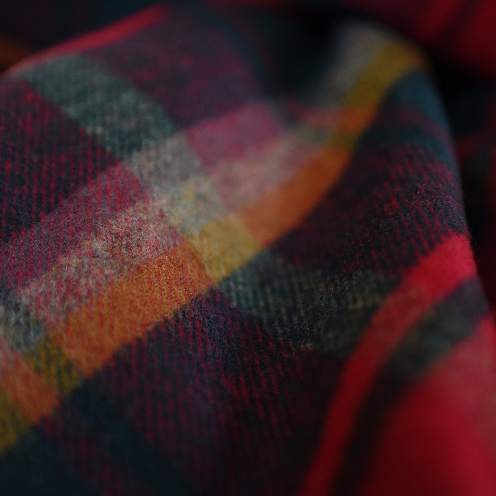 Close-up of the Campbells of Beauly Dark Maple Tartan Lambswool Blanket, featuring a cozy, fuzzy texture and red, yellow, green, and blue plaid pattern inspired by classic Yorkshire style.