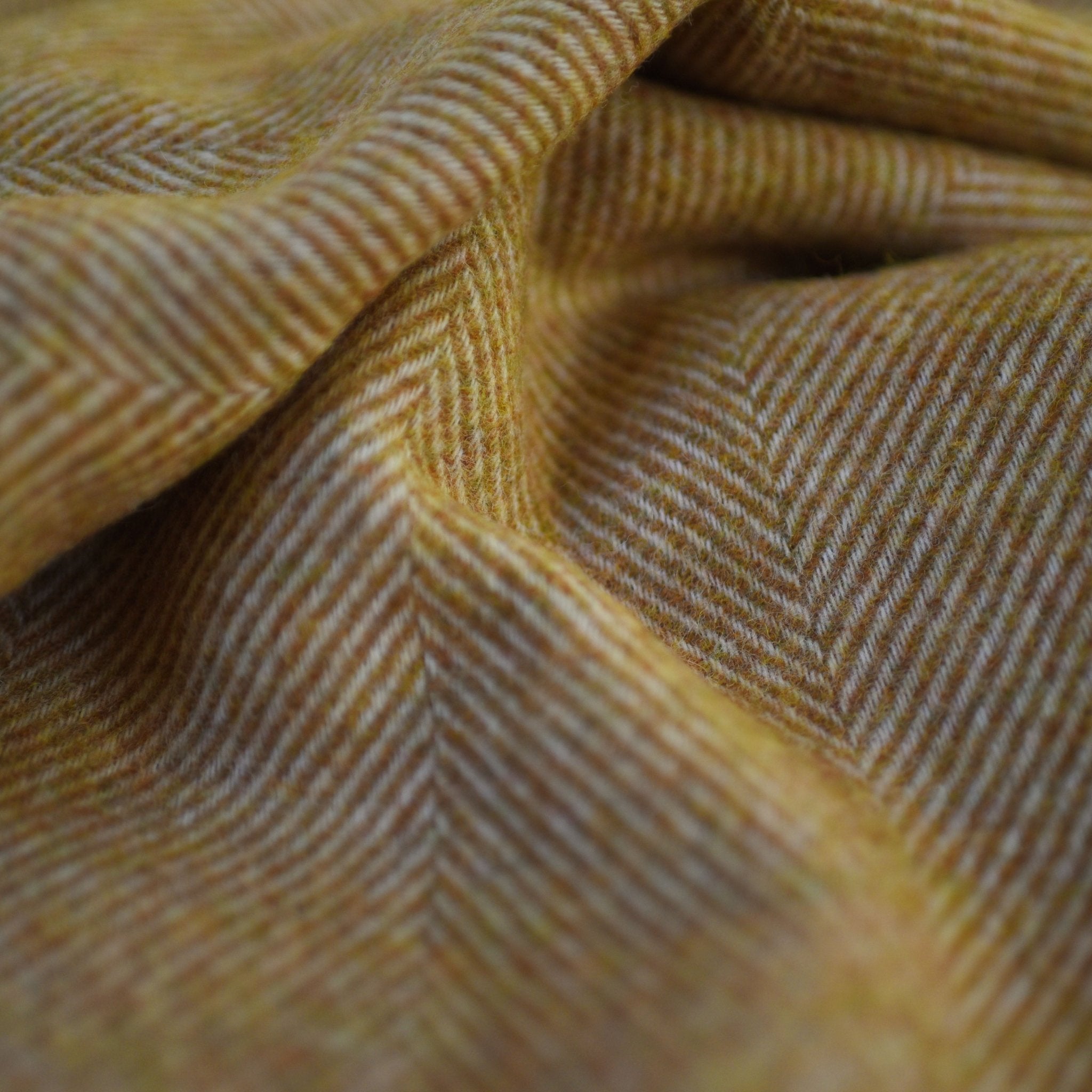 Close-up of the Herringbone Lambswool Blanket by Campbells of Beauly, featuring soft yellow and white tones that highlight the folds and rich texture, emphasizing its luxurious Yorkshire lambswool craftsmanship.