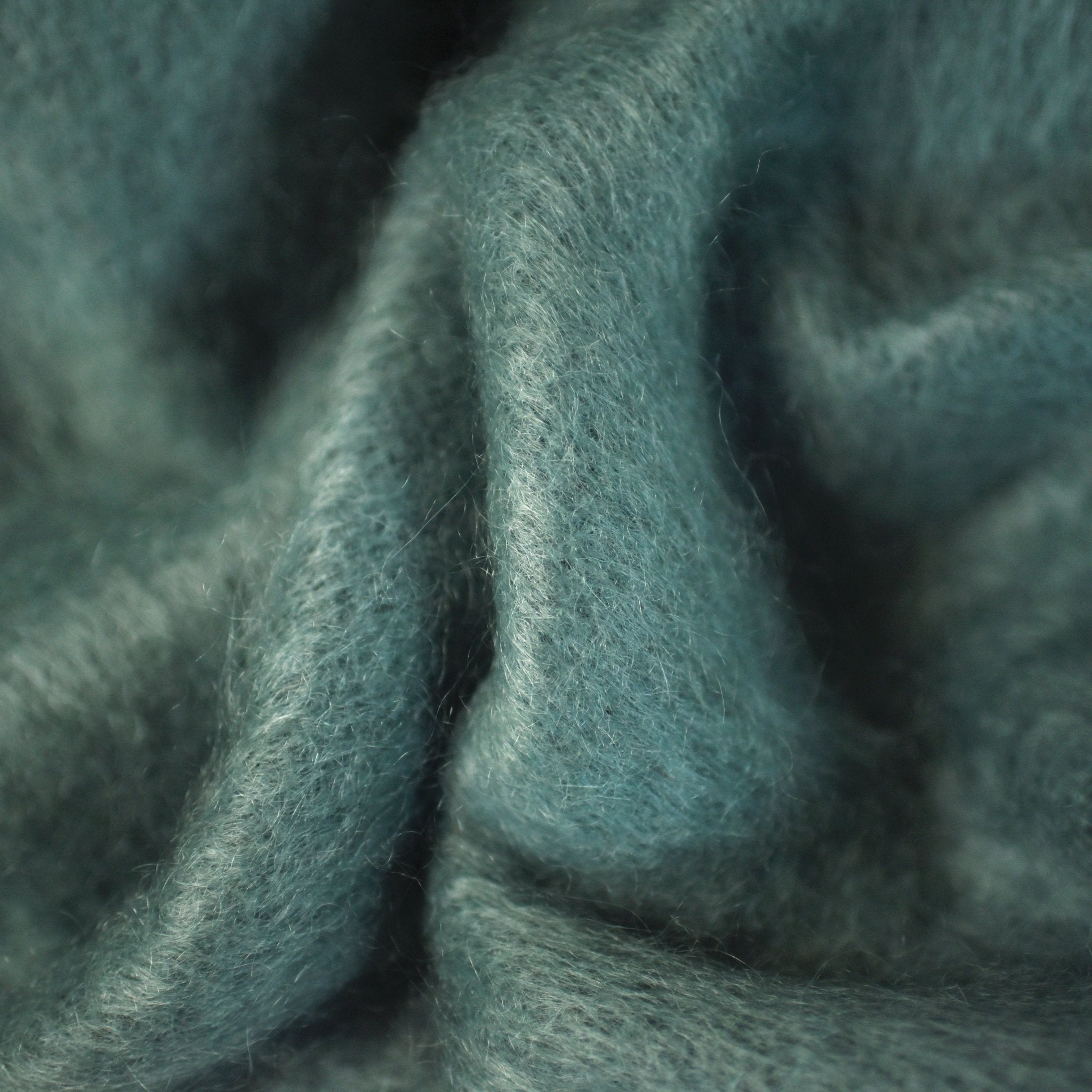 Close-up of soft, teal mohair fabric with a wavy texture and visible fibers, the Mohair Throw by Campbells of Beauly adds cozy warmth and luxury to any space.