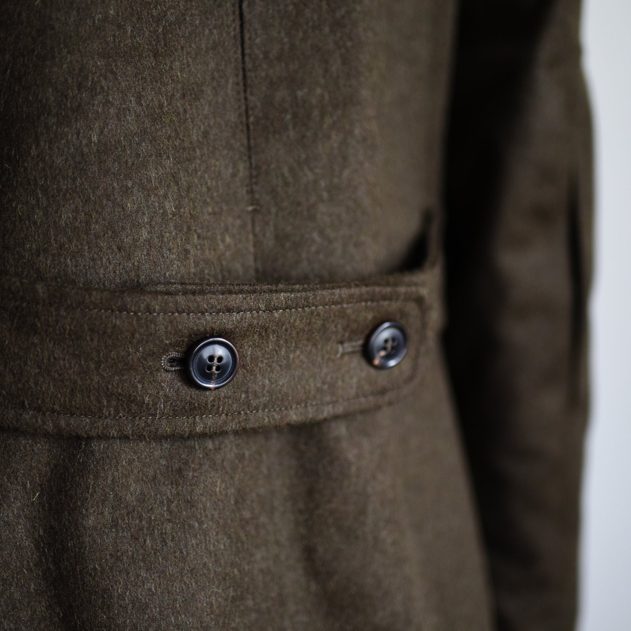 Close-up of the Loden Green Field Coat by Campbells of Beauly, highlighting the waist with a fabric belt and two dark buttons. The Austrian Loden Fabric’s rich texture underscores the quality of this classic outerwear.