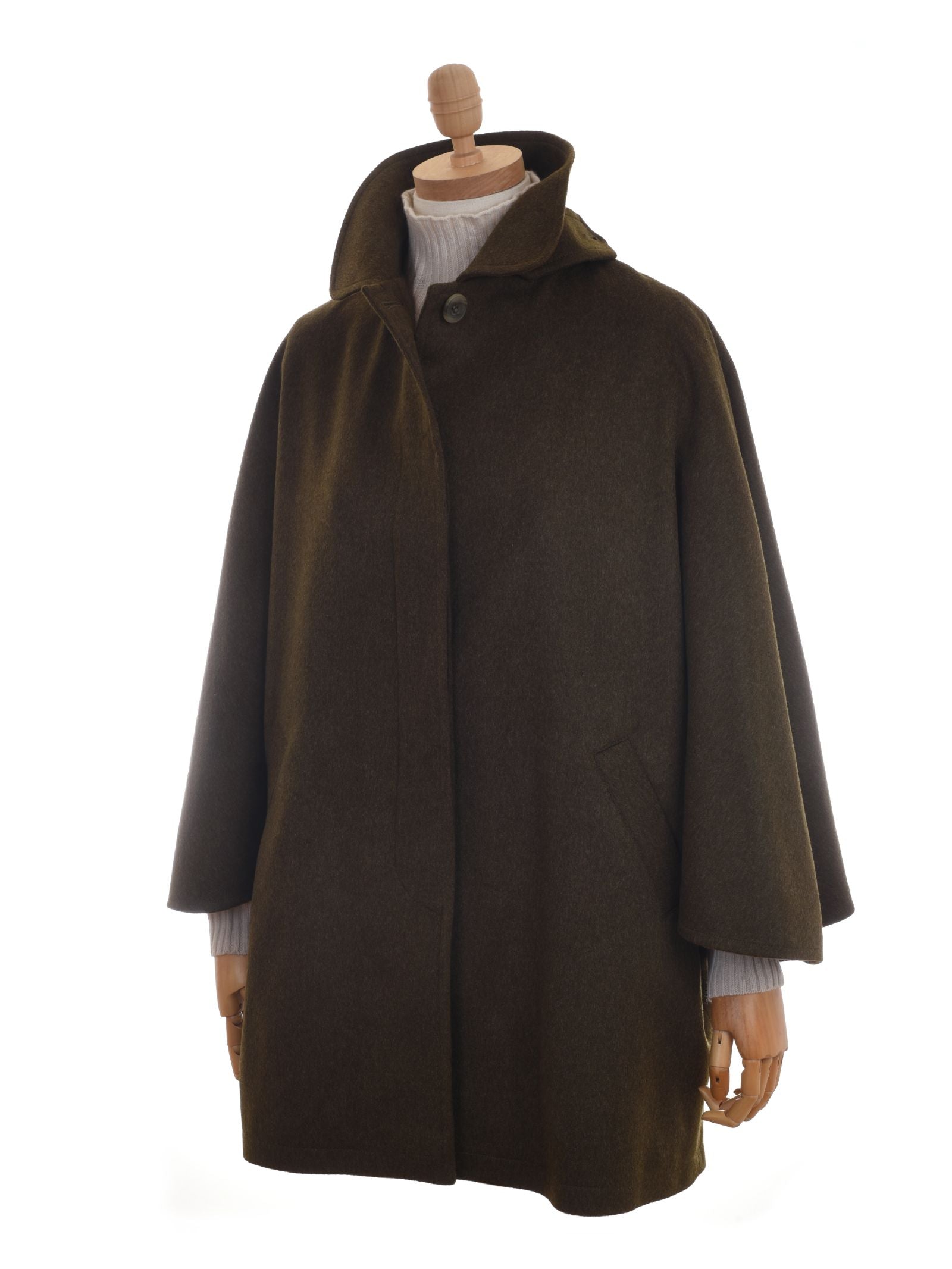 The Campbells of Beauly Loden Green Cape, shown on a mannequin with a white ribbed turtleneck, features heritage-inspired Loden cloth, a high collar, single button closure, and front pockets for timeless style.