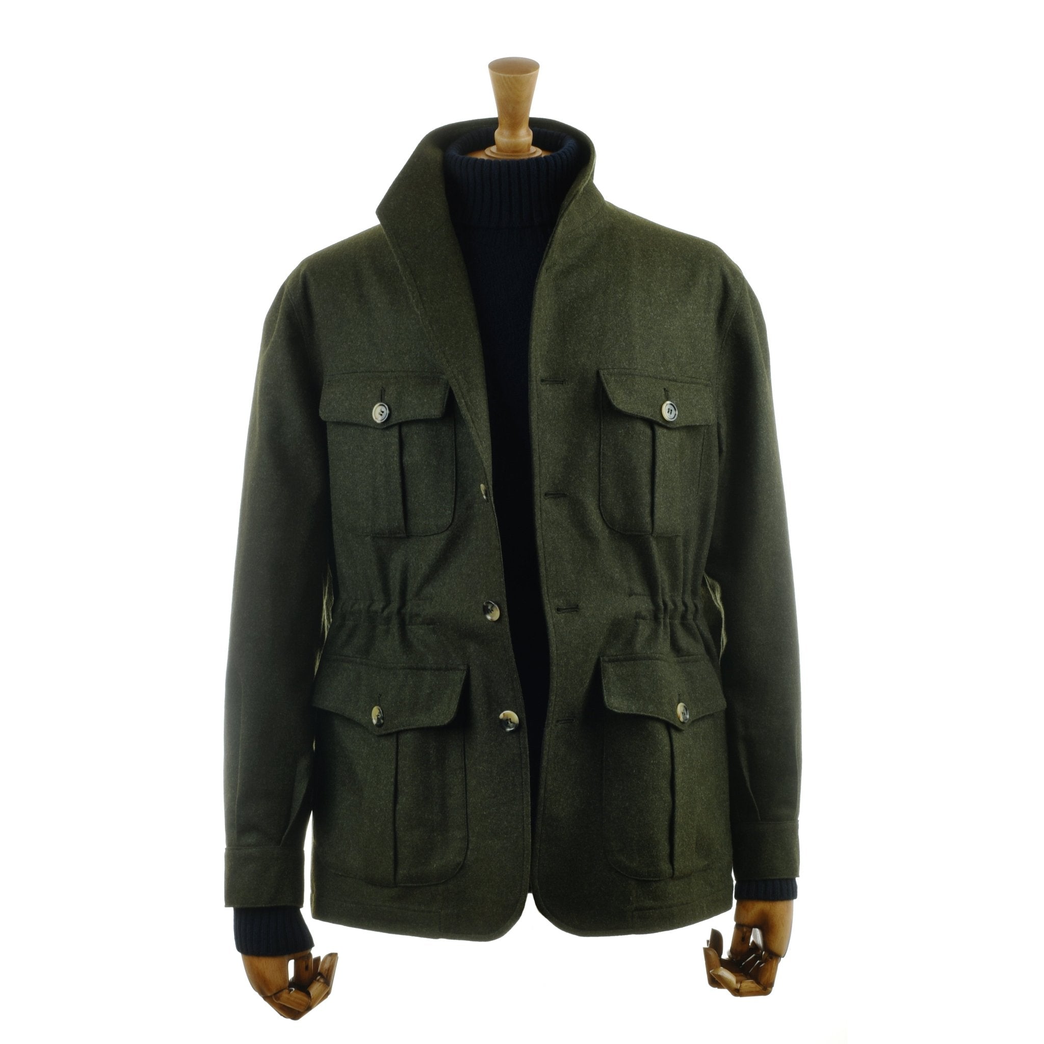 The Campbells of Beauly Field Teba Jacket in Loden, featuring a standing collar, four buttoned front pockets, and drawstring waist, is displayed on a mannequin wearing a black turtleneck sweater.