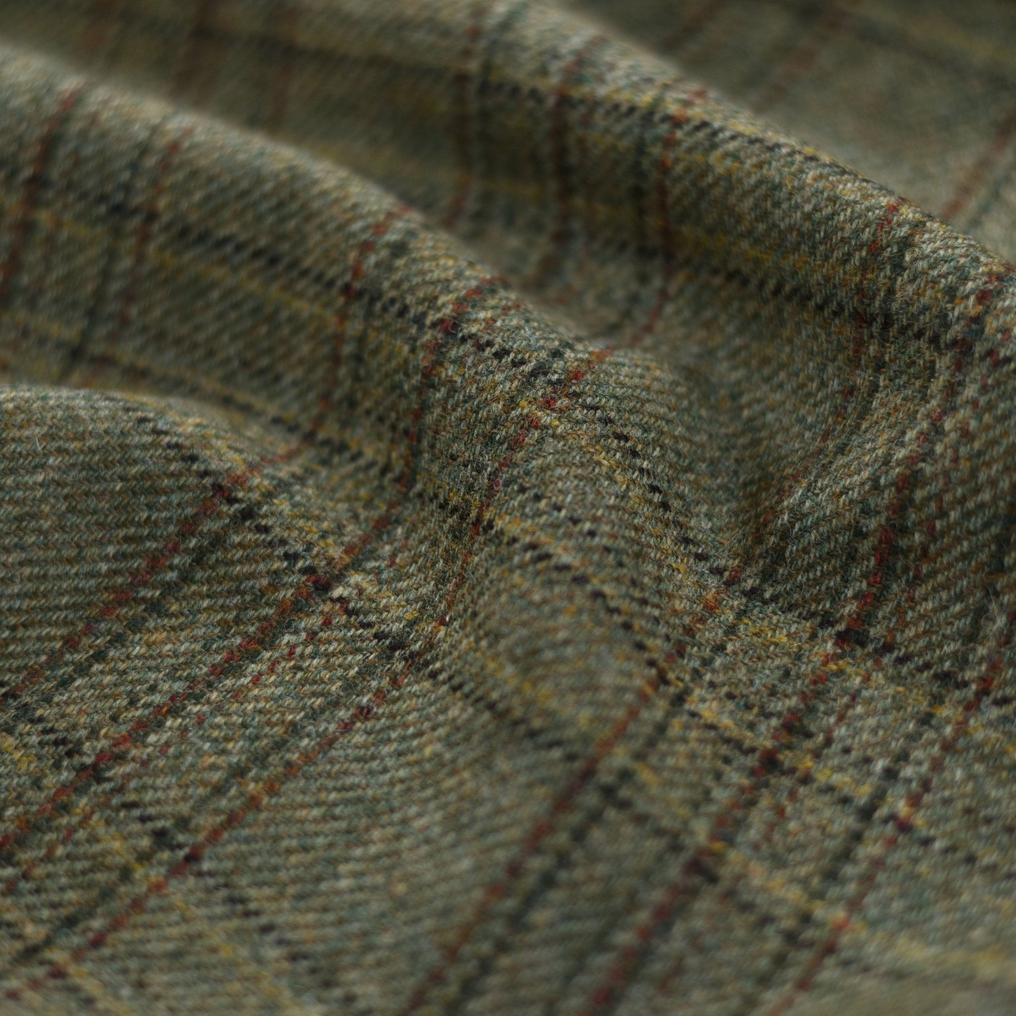 Close-up of Campbells of Beauly House Tweed 81766: a textured wool fabric in green and brown plaid, featuring dark brown and red lines forming squares on its soft, thick surface—evoking traditional Scottish tailoring.