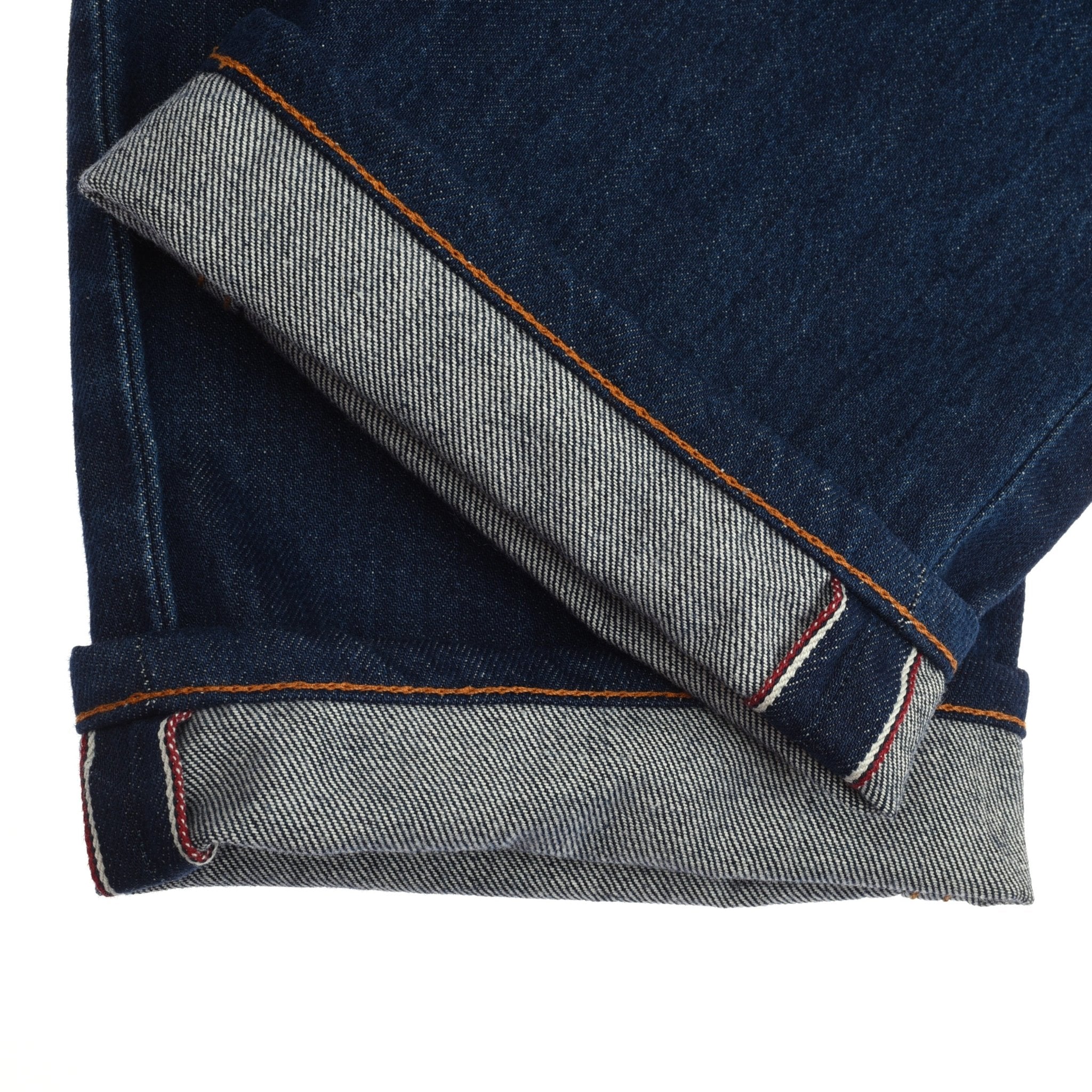 A close-up of two cuffs of Campbells of Beauly Denim Jeans in medium-dark indigo selvedge, turned up to show the red and white stitching, crafted from 100% cotton.