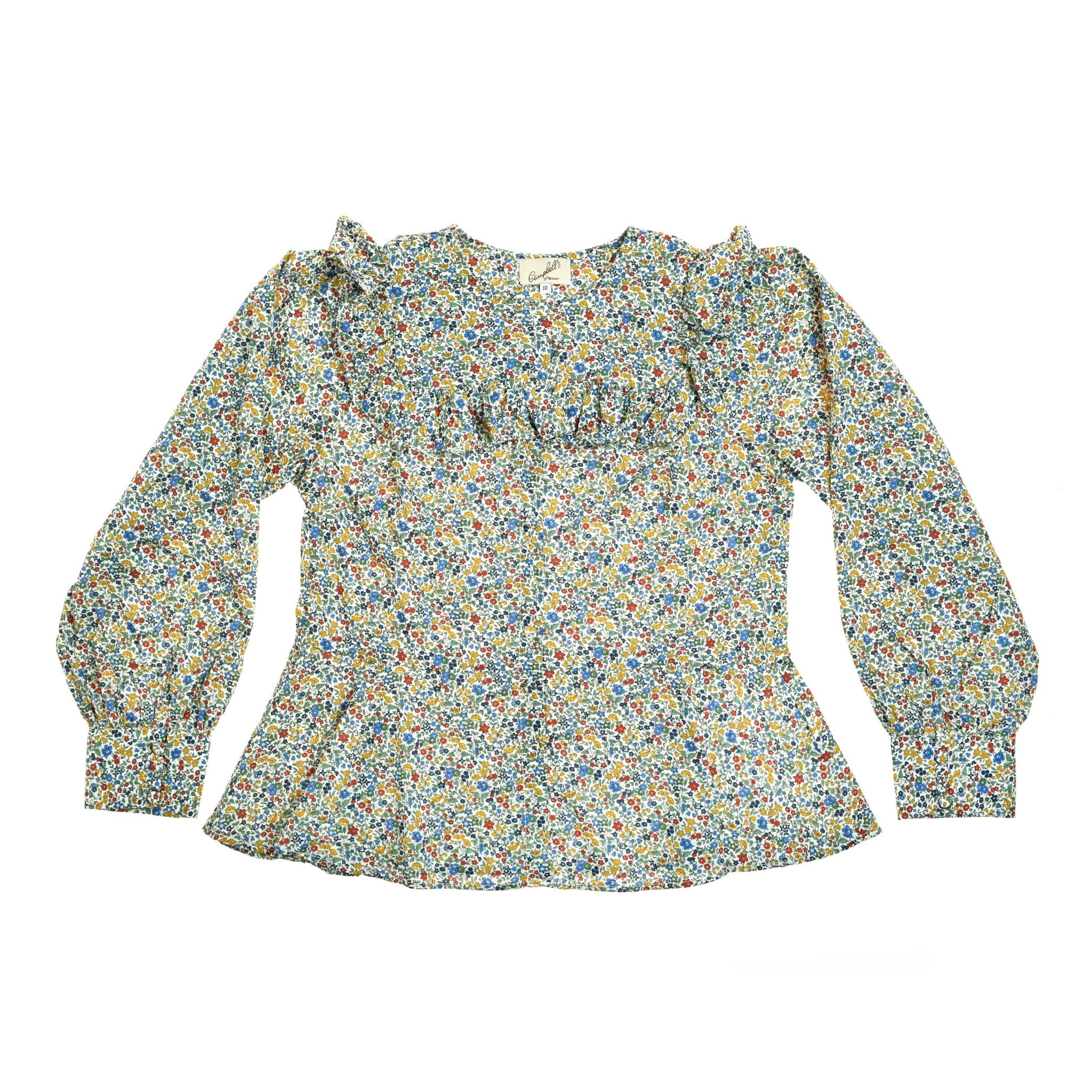 The Liberty Print Peplum Shirt by Campbells of Beauly features a colorful floral Tana Lawn cotton, ruffled chest, round neck, fitted waist, and puffed sleeves for a flattering peplum silhouette.