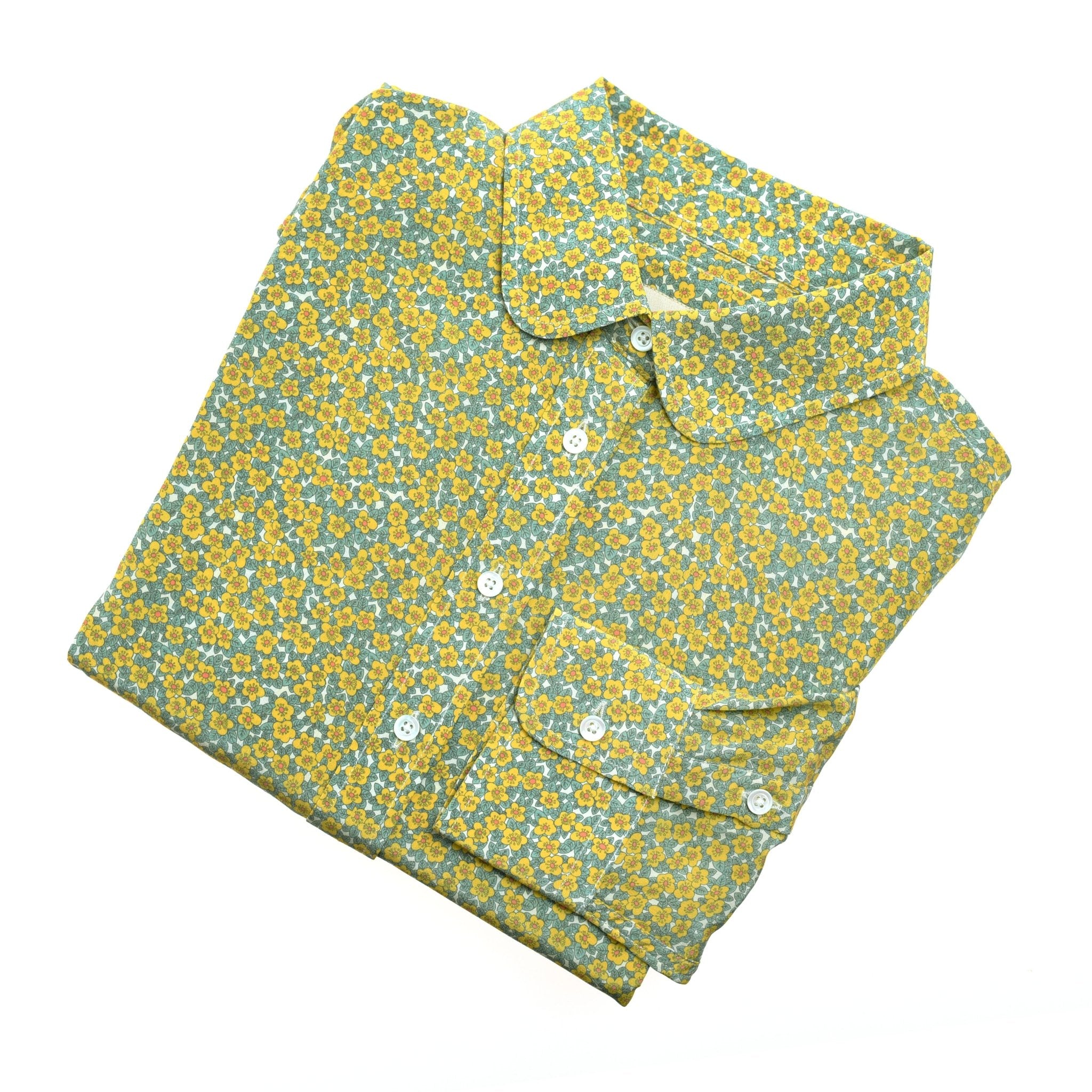 A neatly folded Campbells of Beauly Liberty Print Silk Shirt, 100% silk with a yellow and blue floral pattern and white buttons, made in Portugal, shown on a white background.