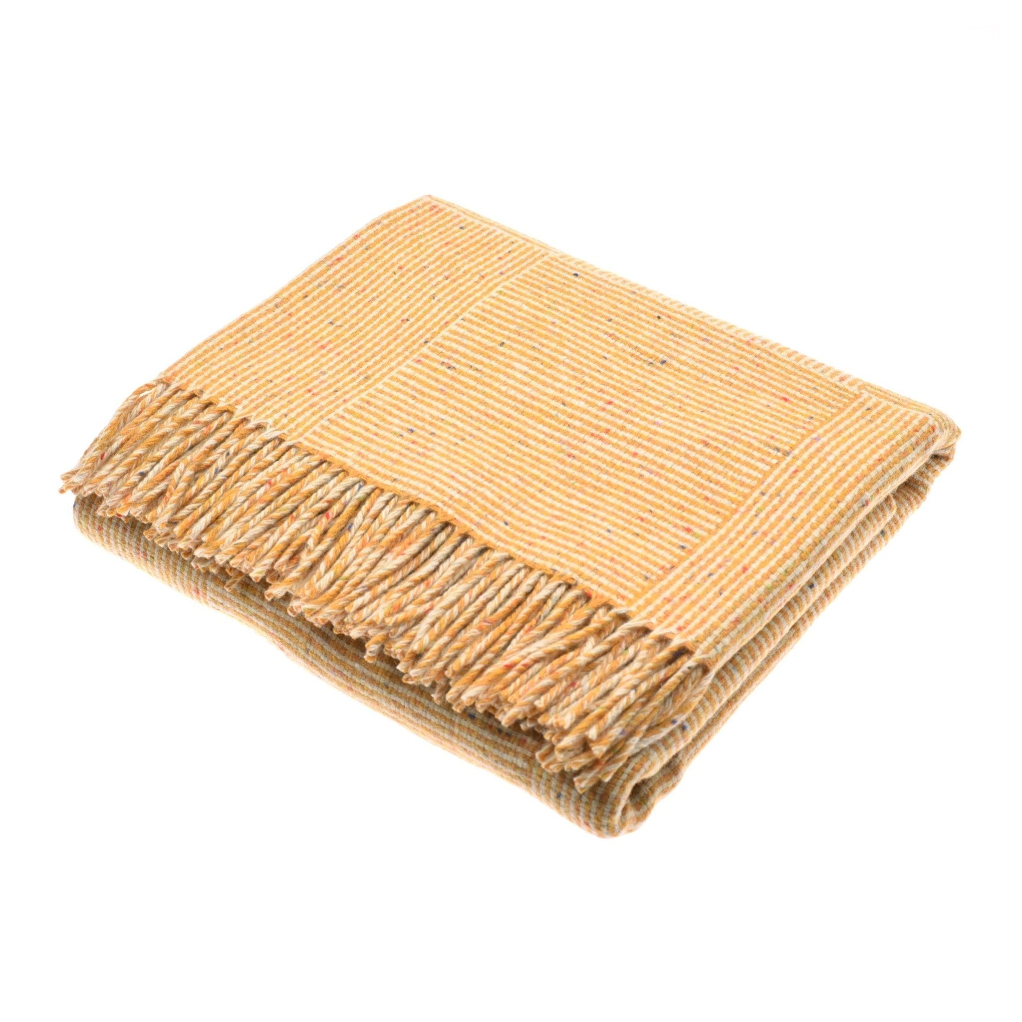 The Cabrich Lambswool Throw by Campbells of Beauly, in Gorse, features a beige and yellow striped pattern with fringed edges and a subtle basket weave design, displayed on a white background.