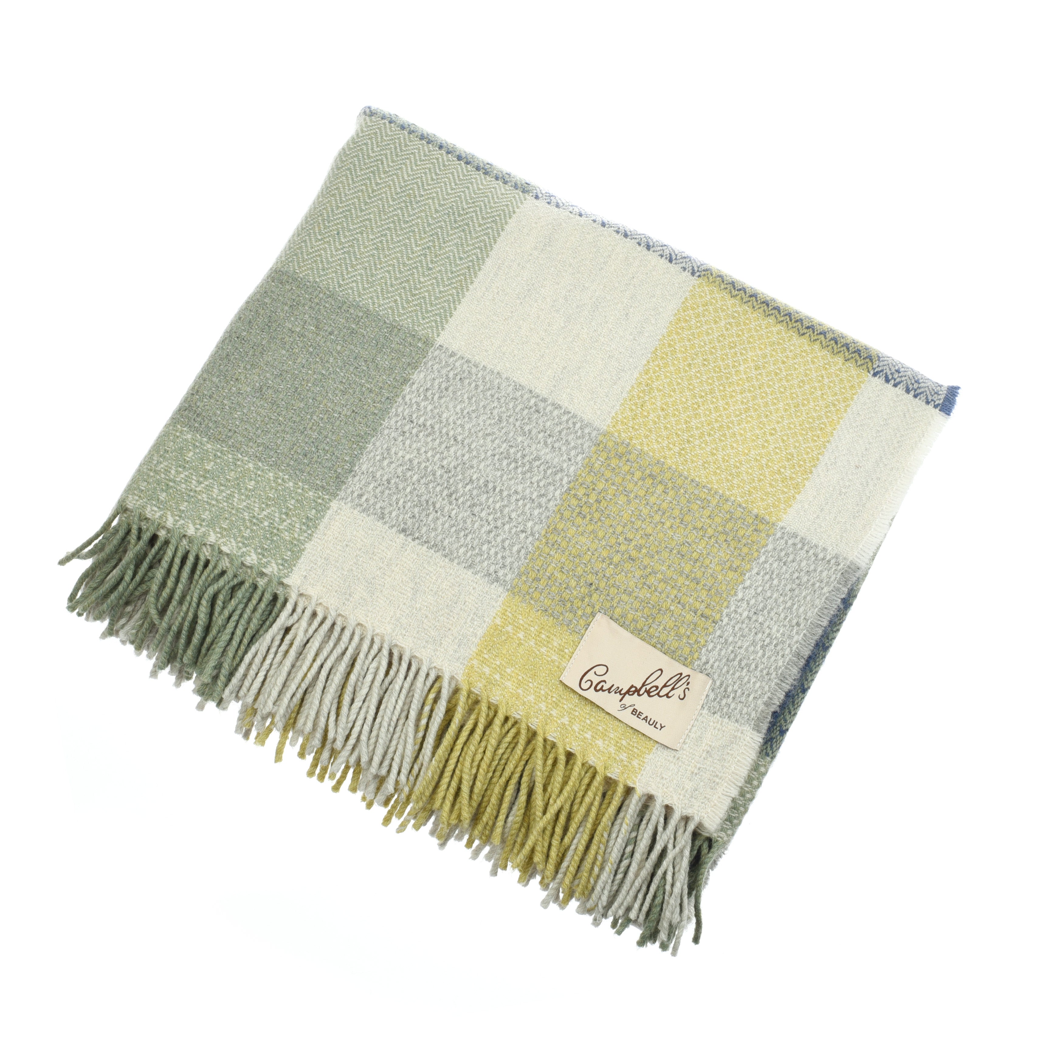 The Patchwork Throw by Campbell’s of Beauly is a neatly folded lambswool blanket in soft green, yellow, grey, and cream check. Traditionally woven with fringed edges and a sewn brand label, the thick fabric looks cozy and inviting.