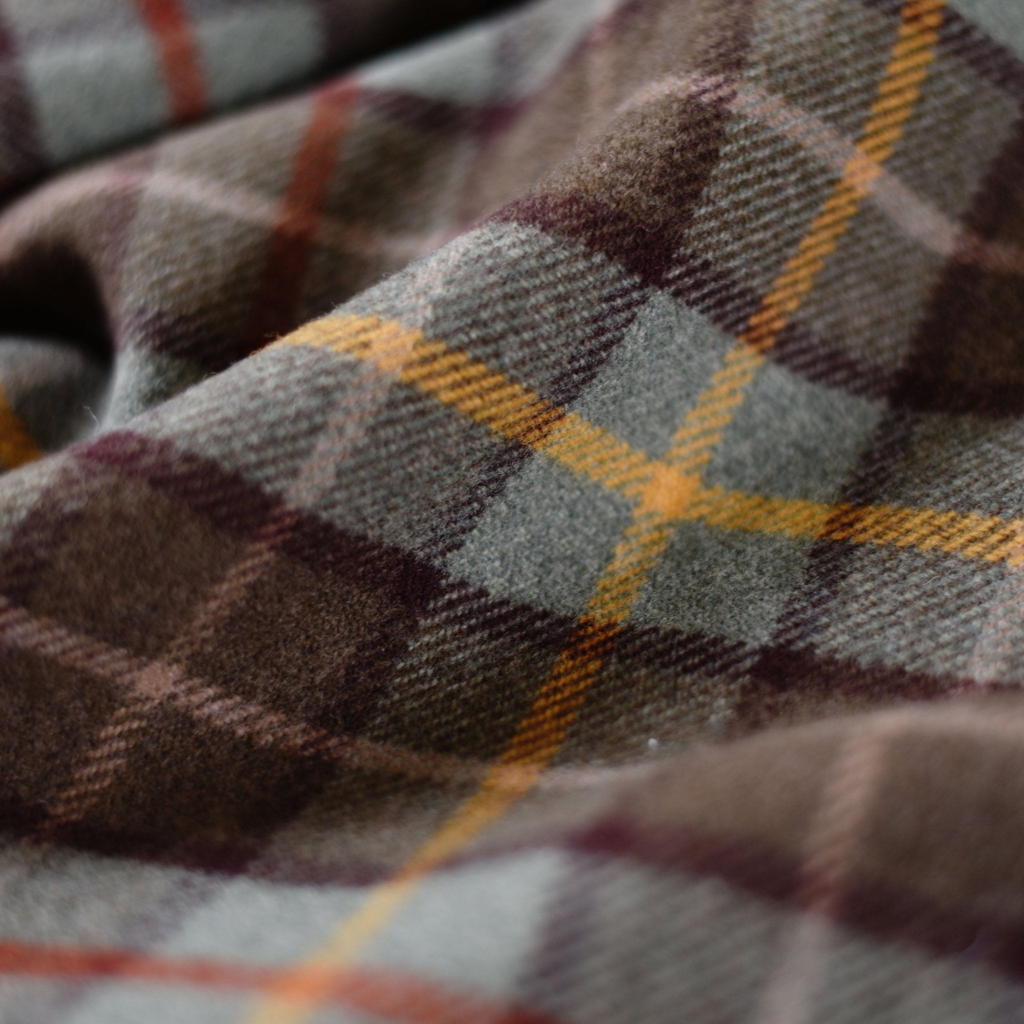 A close-up of the Lavender Throw by Campbells of Beauly, a soft lambswool blanket with a plaid pattern in brown, gray, and cream, accented with intersecting yellow and burgundy lines—crafted in the Scottish Borders.
