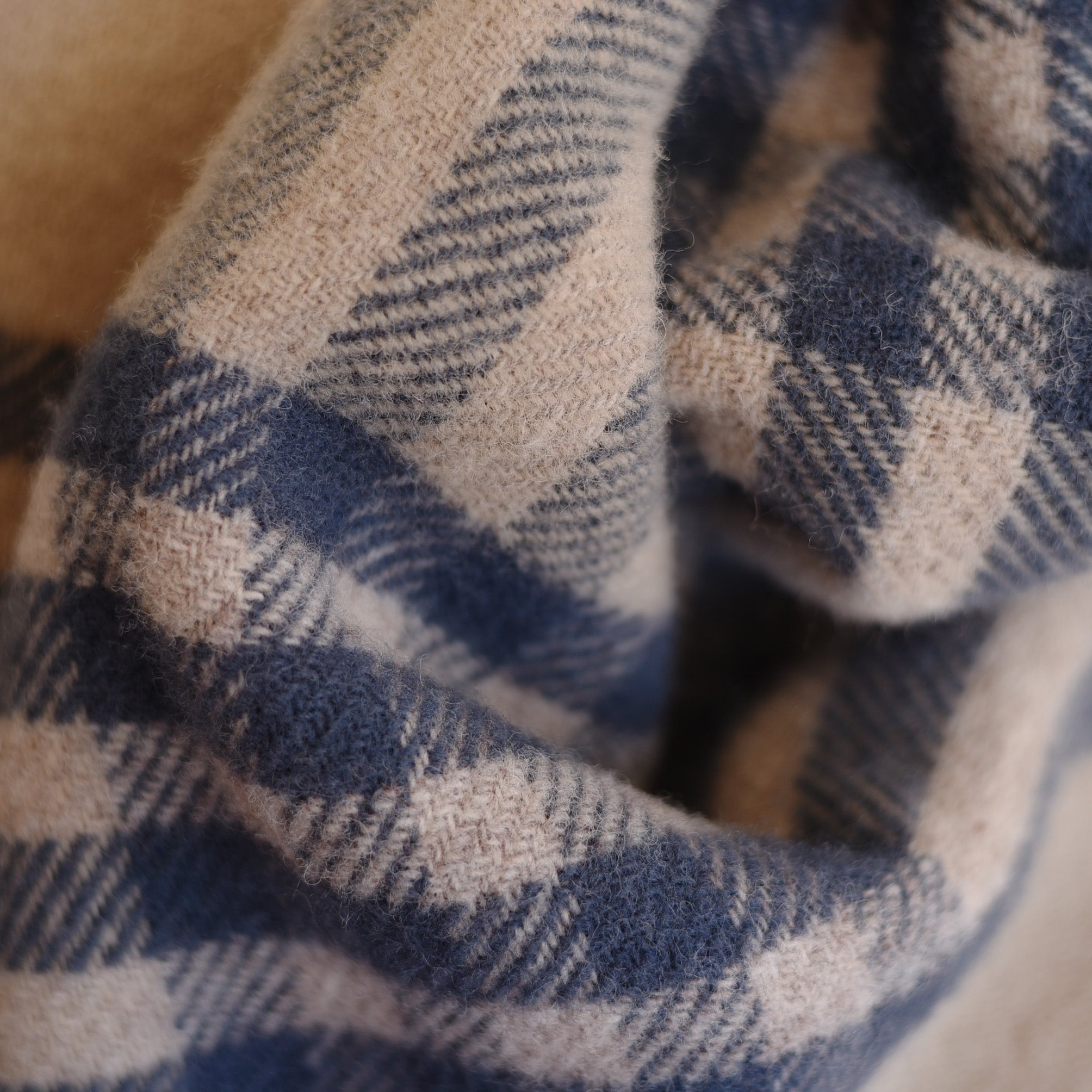 Close-up of the Tarradale Lambswool Throw by Campbells of Beauly, showing its light beige and navy check pattern, soft textured fibers, and gentle folds—showcasing British craftsmanship.