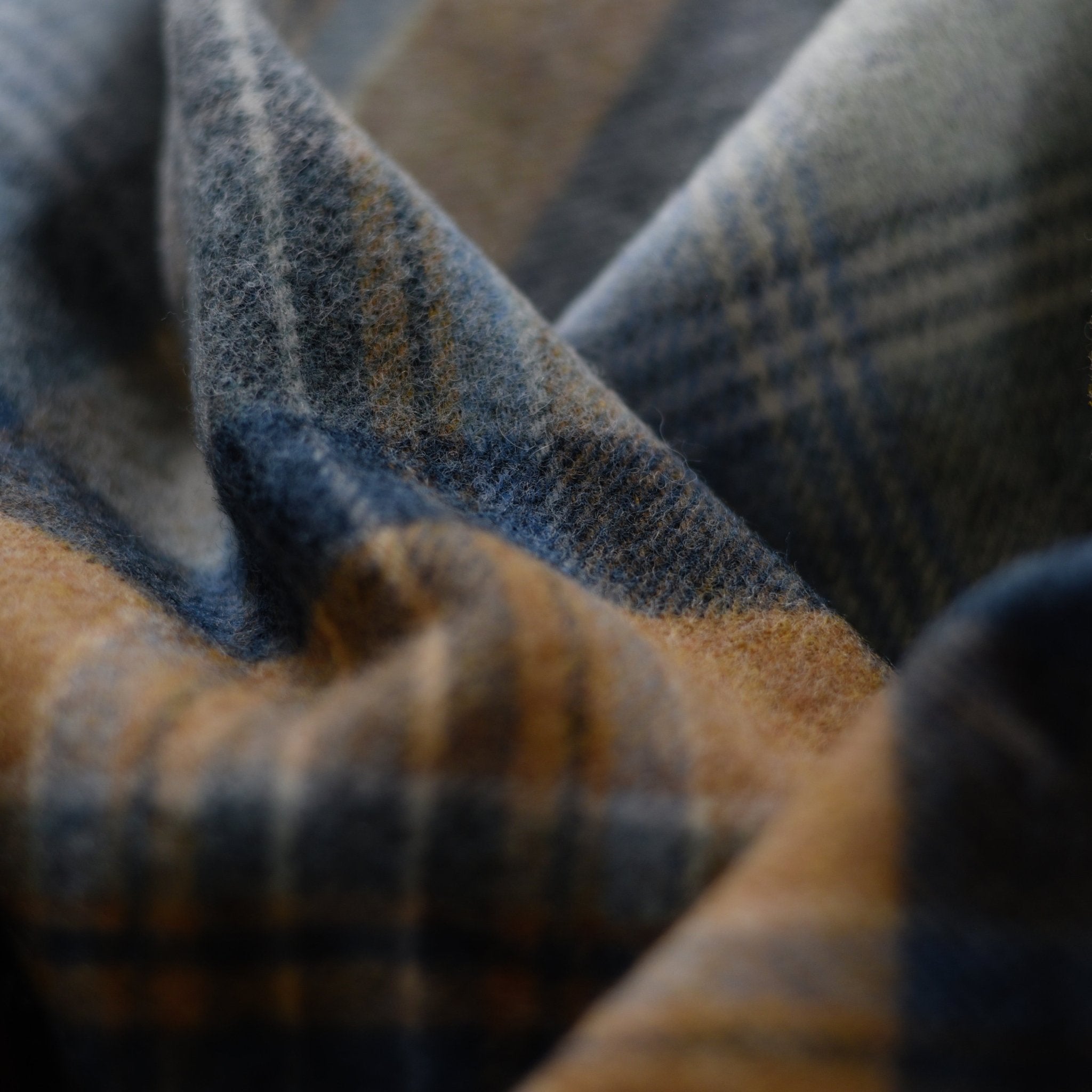 Close-up of the Orrin Lambswool Throw by Campbells of Beauly, featuring a soft plaid in blue, gray, and brown with a fuzzy texture—a cozy, timeless piece inspired by Yorkshire heritage.