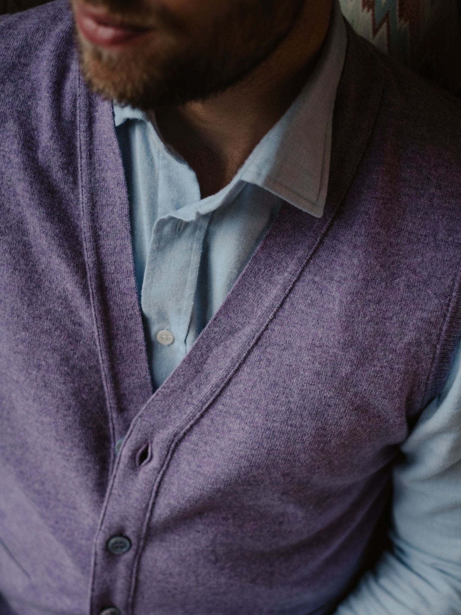 A man with a short beard wears a light blue shirt beneath the lavender Auld Stock Geelong Lambswool Button Waistcoat by Campbell's of Beauly. The cropped image highlights his lower face and upper torso, radiating refined, country-inspired charm.