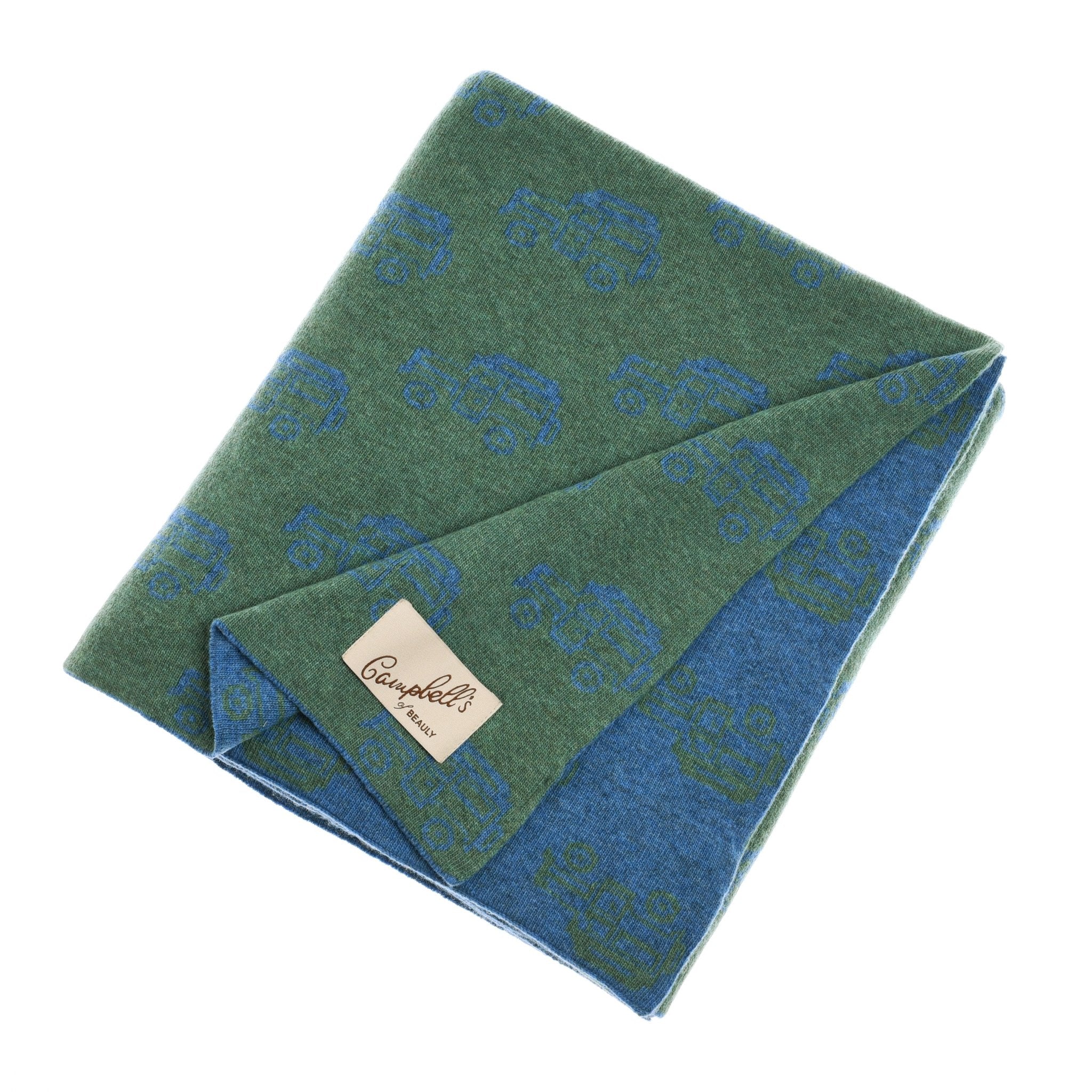 A folded green and blue Land Rover Defender lambswool blanket by Campbells of Beauly, featuring a repeating car pattern and a beige Campbells 1920 tag sewn on one corner.