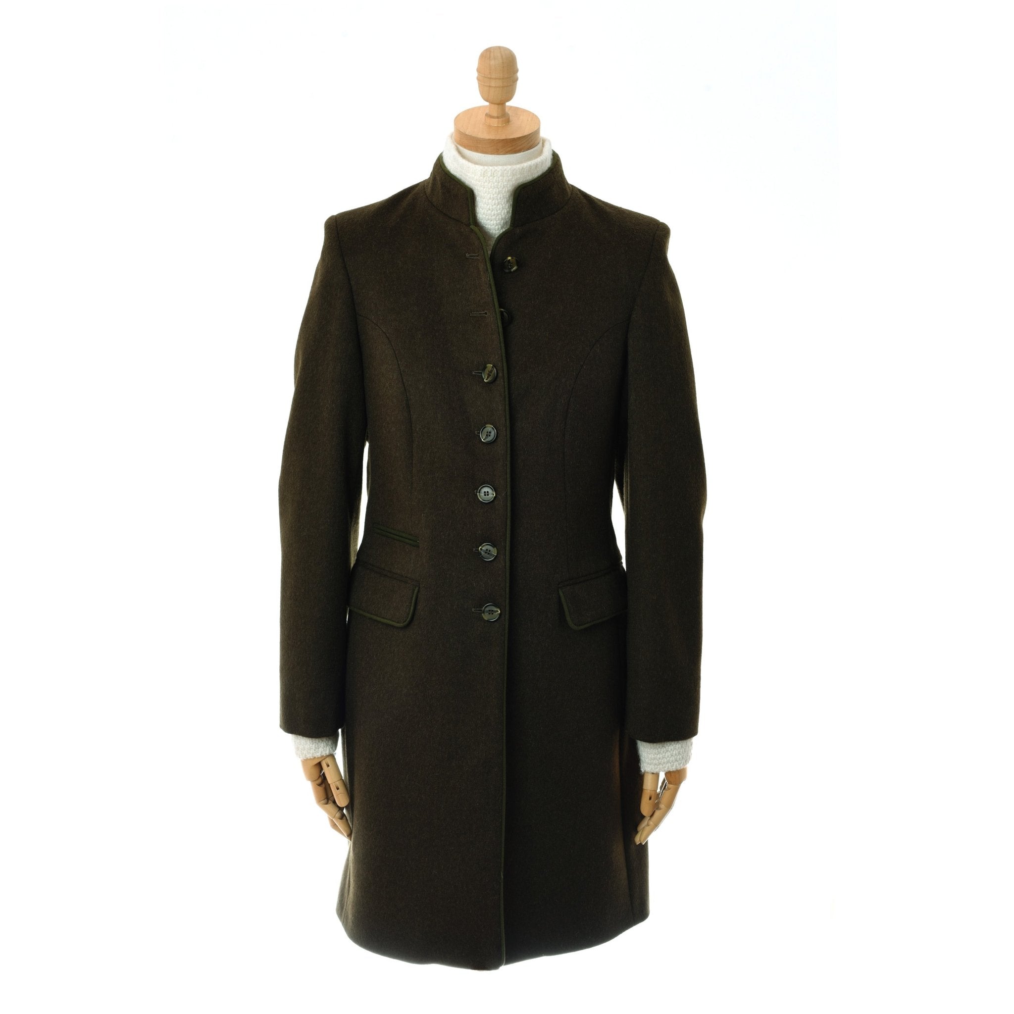 The Campbells of Beauly Loden Green Millie Coat is a dark brown, knee-length coat crafted from Austrian loden wool, featuring a Nehru collar, front buttons, and flap pockets, shown on a mannequin with a light turtleneck against a white background.