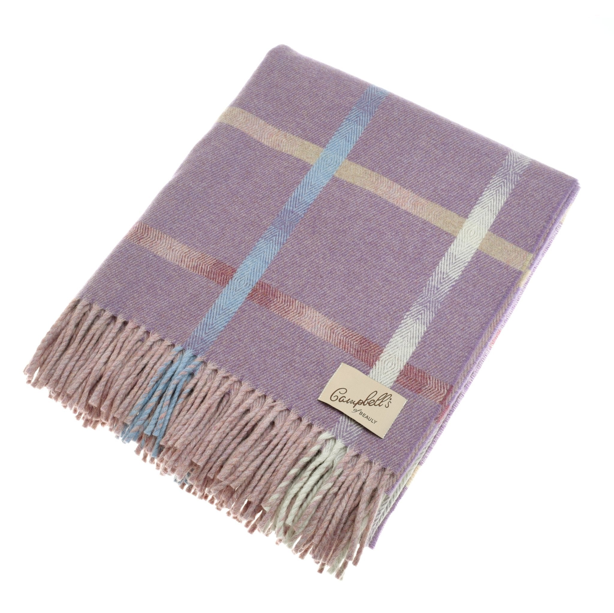 The Maree Lambswool Blanket by Campbell’s of Beauly is a folded, fringed lavender throw with a cream, blue, and pink windowpane pattern, crafted in Scotland and finished with a beige Campbell’s of Beauly label sewn on one corner.