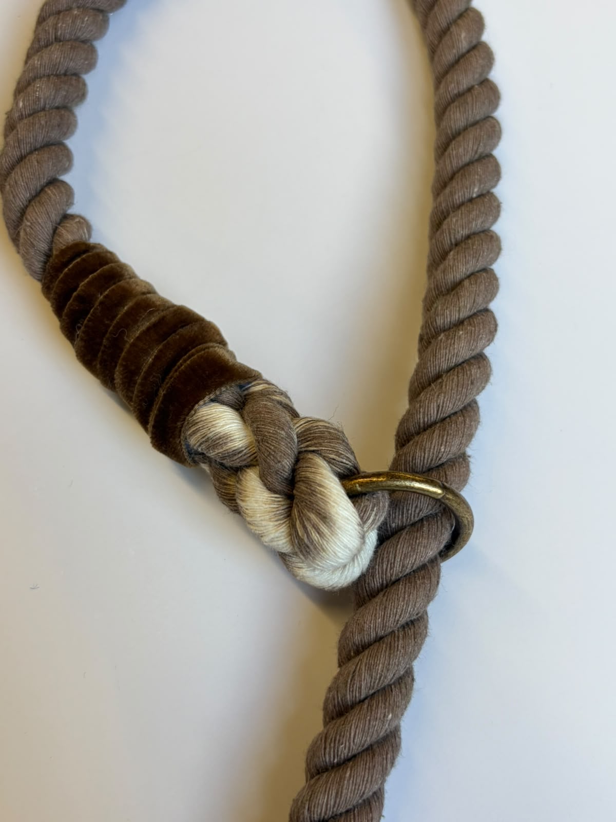 The House Tweed Slip Lead by Campbell's of Beauly—a thick, brown rope with a knot, wrapped with dark brown and white threads near a brass ring—is lying on a white surface.