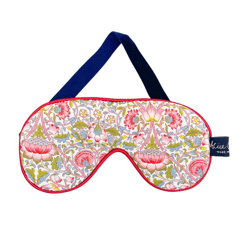 The Alice Caroline Liberty Print Eye Mask has a velvet-padded backing, a navy strap, pink trim, and floral red, pink, and green designs on white fabric with a fabric tag on the right side for stylish, restful sleep.