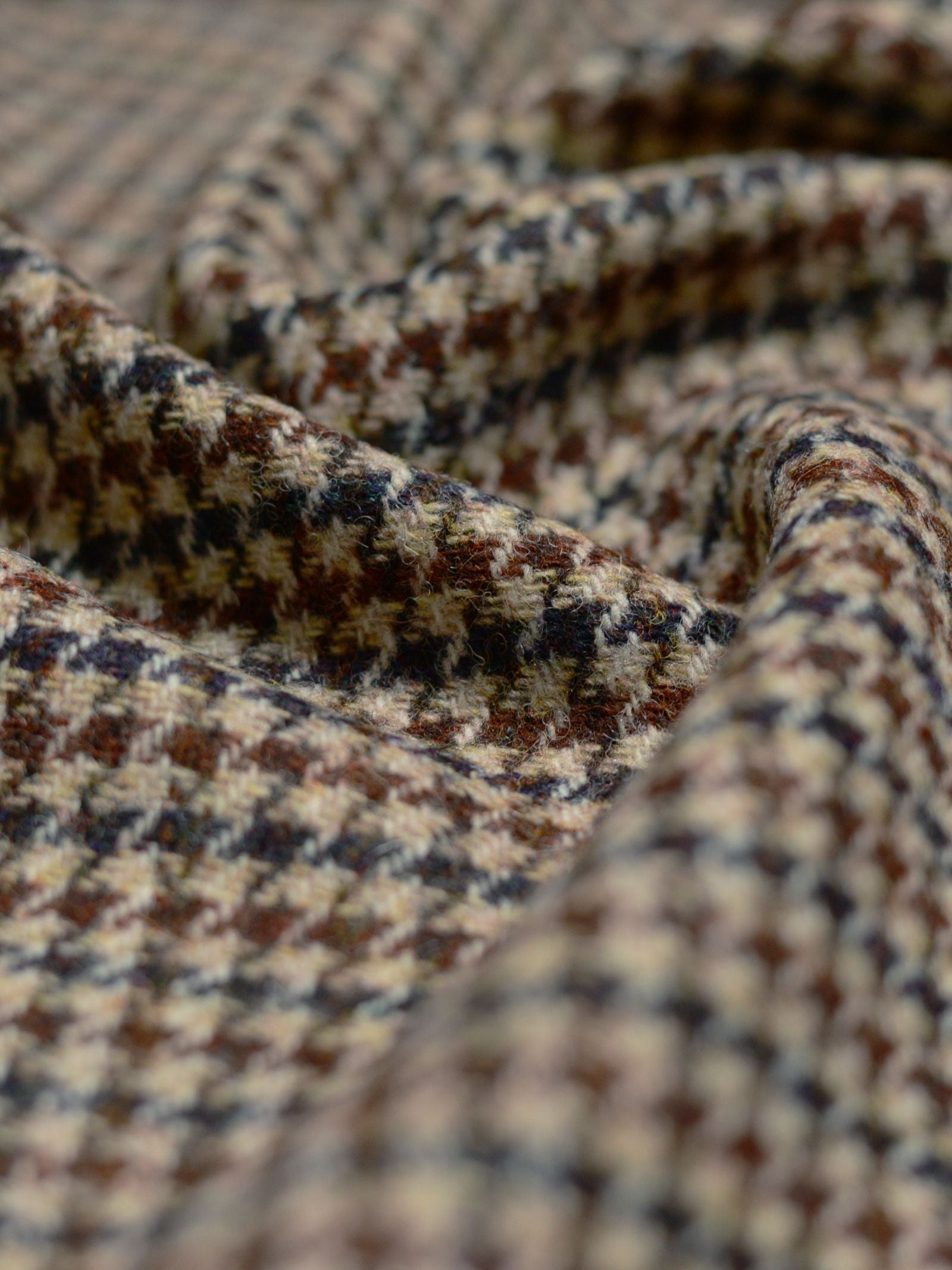 Close-up of House Tweed 93896 by Campbell's of Beauly, featuring soft folds and creases in a brown, beige, and black houndstooth pattern—a tribute to Scottish weaving heritage.
