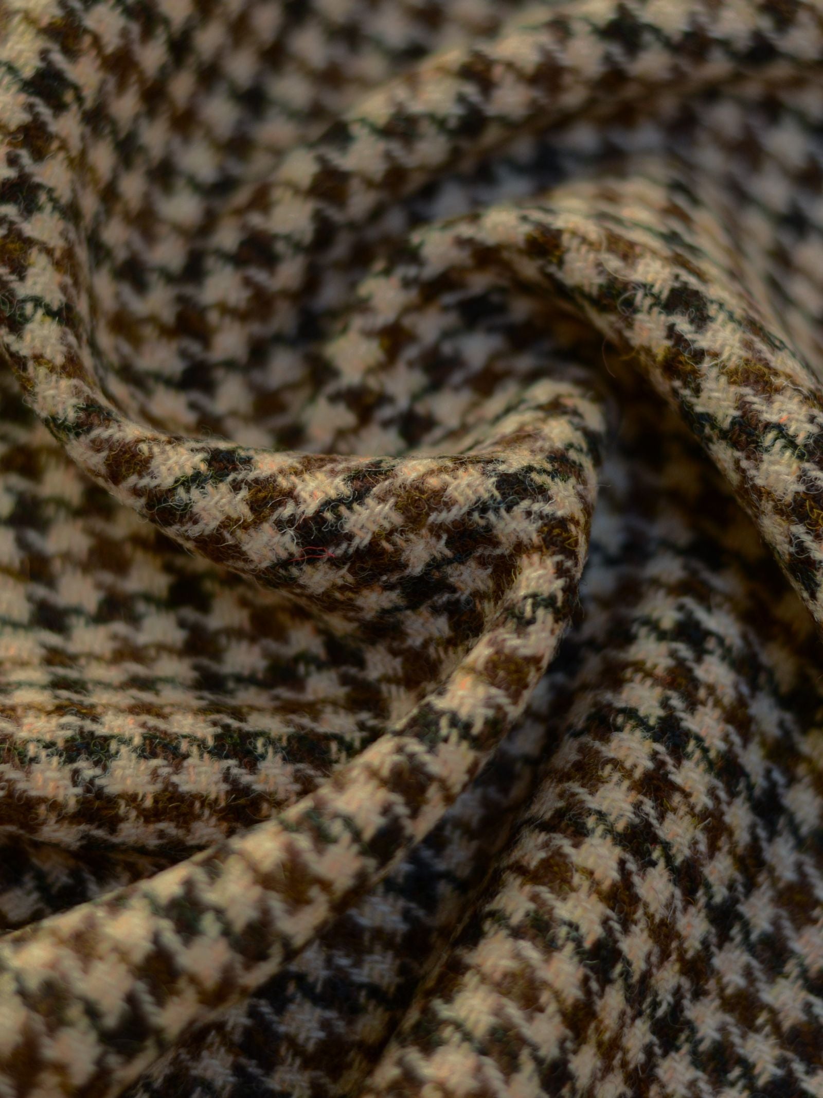 Close-up of House Tweed 93909 by Campbell's of Beauly, a featherweight fabric with a brown, black, and beige houndstooth pattern, softly folded to highlight its texture and intricate design.