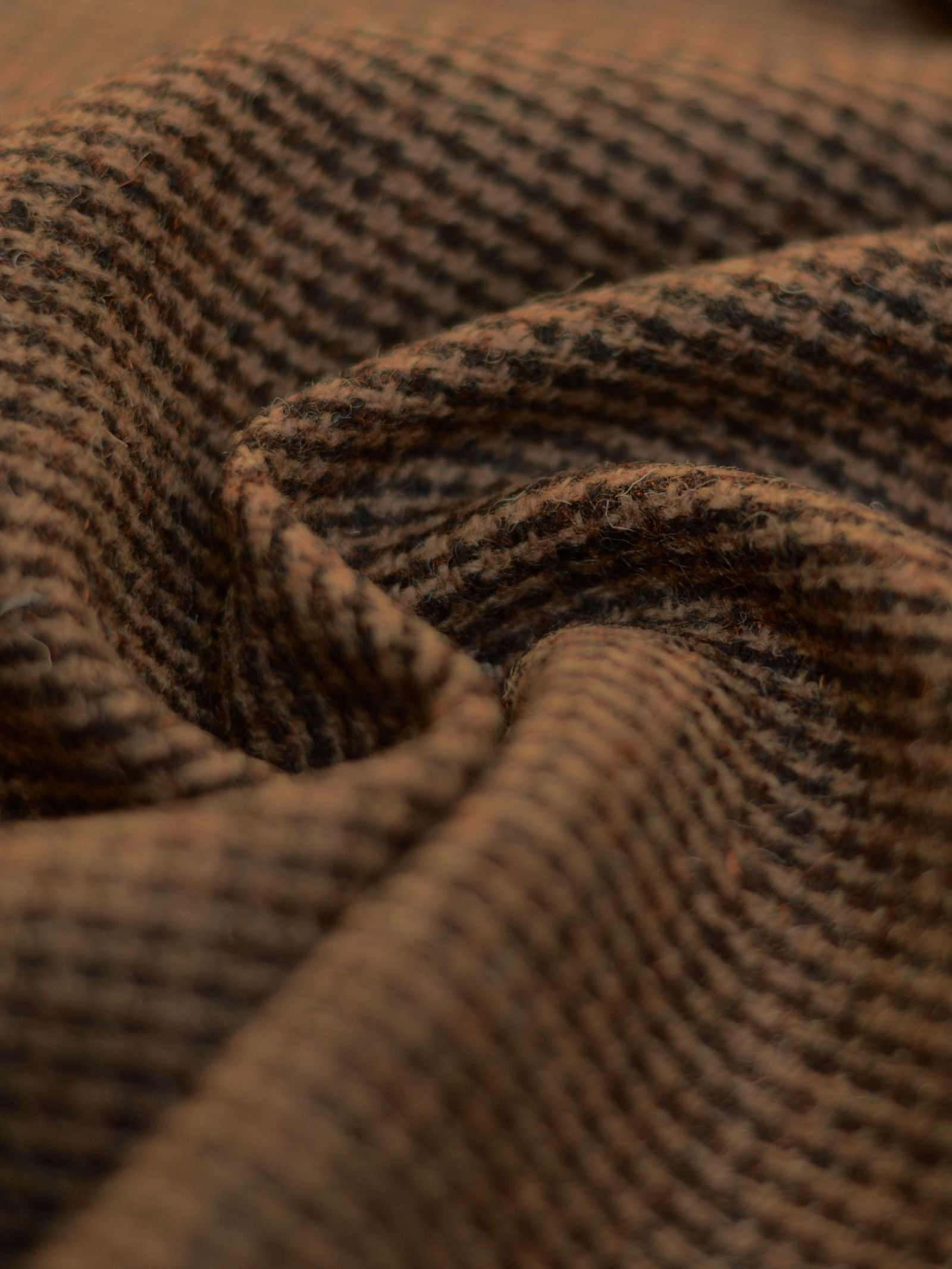 Close-up of House Tweed 93905 by Campbell's of Beauly—a featherweight, brown and black houndstooth fabric featuring a soft, textured surface and gentle folds, exemplifying fine Scottish weaving.