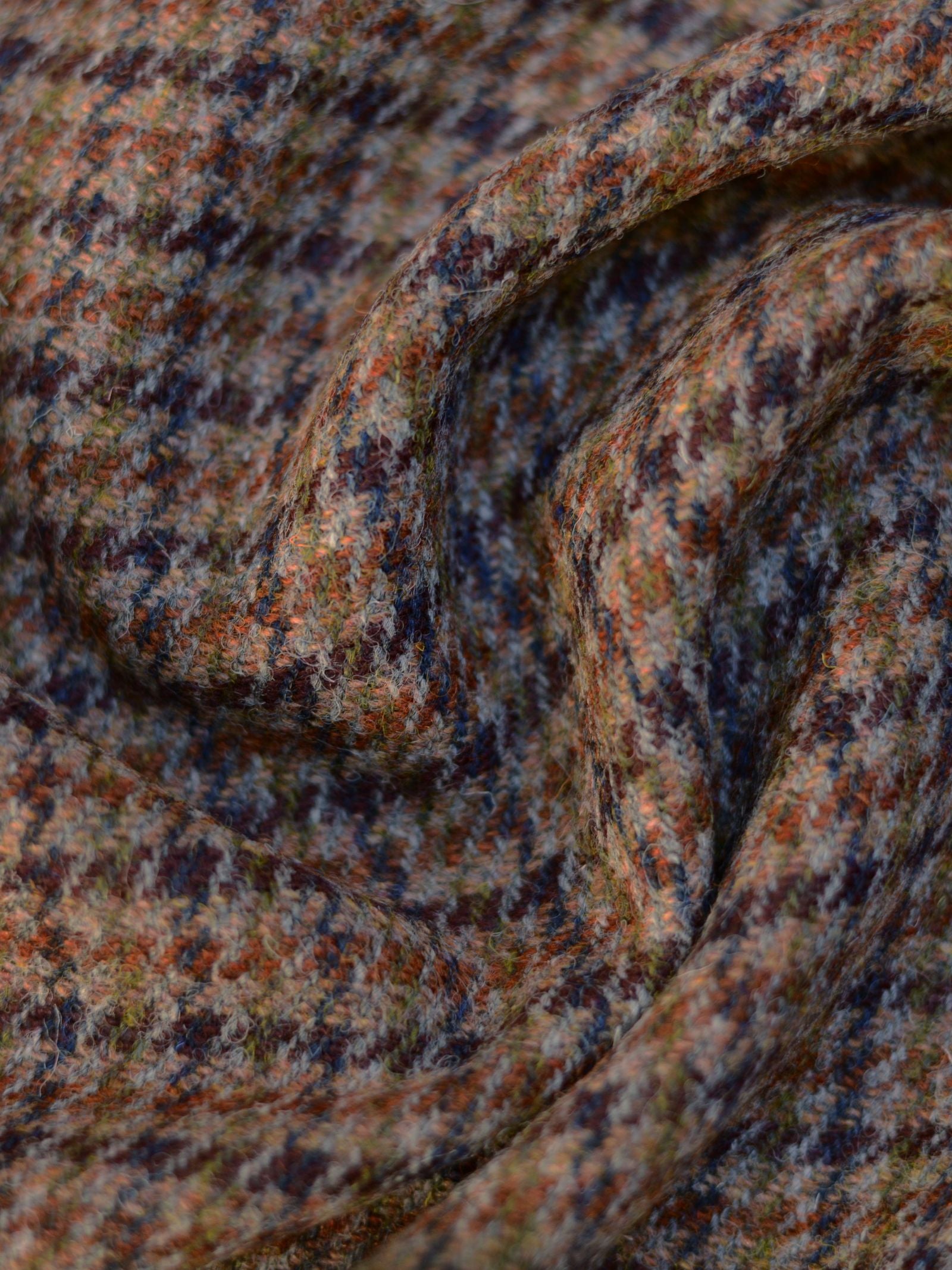 A close-up of House Tweed 93914 by Campbell's of Beauly shows textured wool fabric in a brown, orange, blue, and green houndstooth pattern—evoking classic Scottish weaving in the style of Harris Tweed.