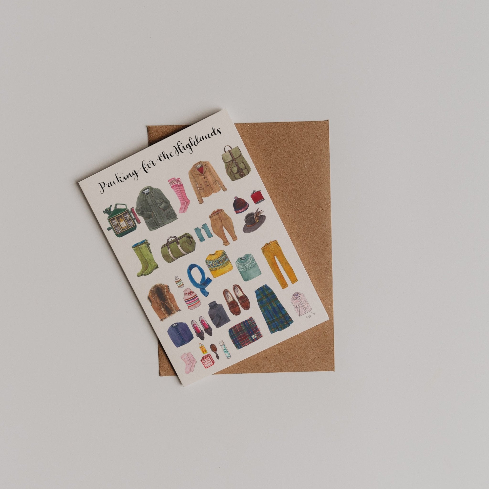 Packing for the Highlands Greeting Card by Campbells of Beauly features illustrated clothing, shoes, and travel items—perfect as a thank you note. Shown atop a brown envelope on a white background.