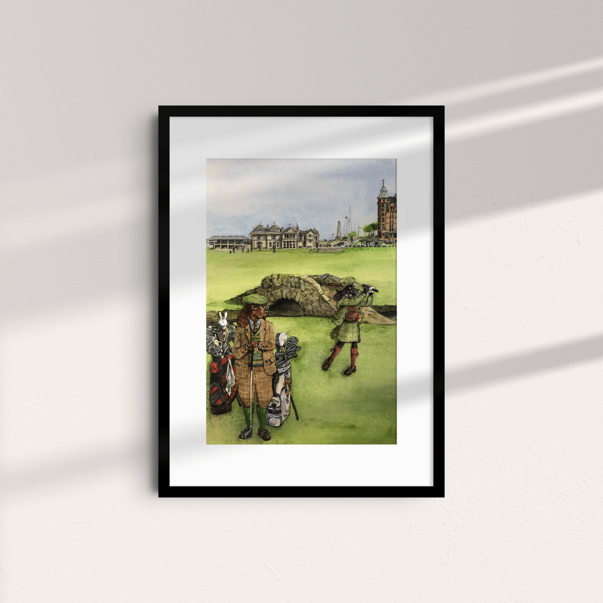 Unframed print by Campbell’s of Beauly shows two golfers in vintage attire on a green course with historic buildings and the Swilcan Bridge. Sunlight creates gentle shadows, highlighting this exclusive Swilcan Bridge Cocker illustration.