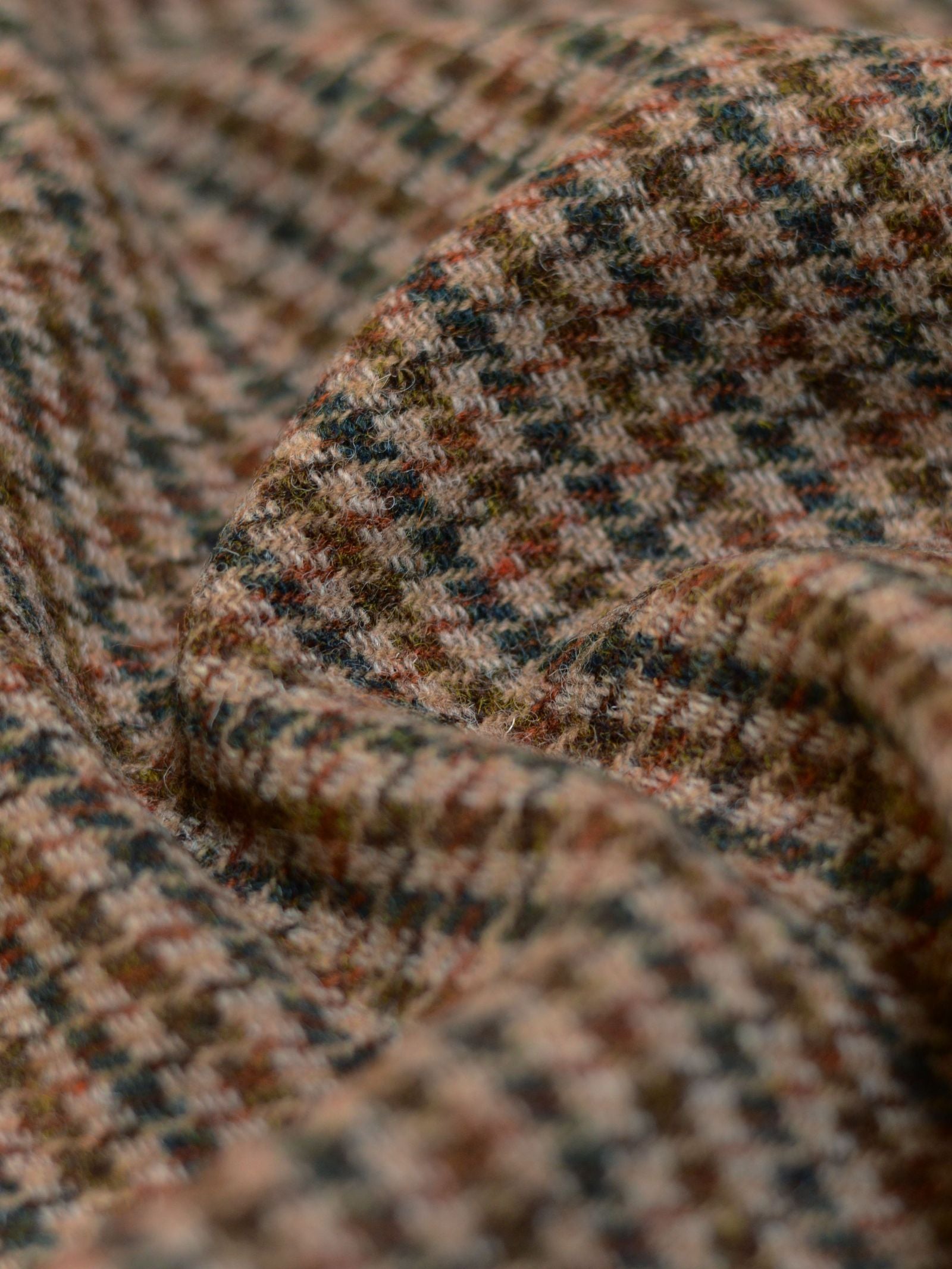 Close-up of House Tweed 93887 by Campbell's of Beauly, featuring a brown, green, and beige houndstooth pattern with classic Scottish texture and soft woven fibers.