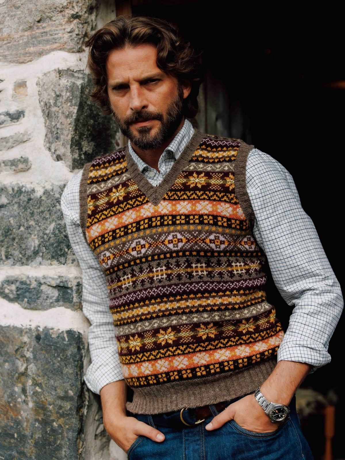 Man wearing a colorful Campbell’s of Beauly Fairisle Slipover over a light-colored grid-check shirt.