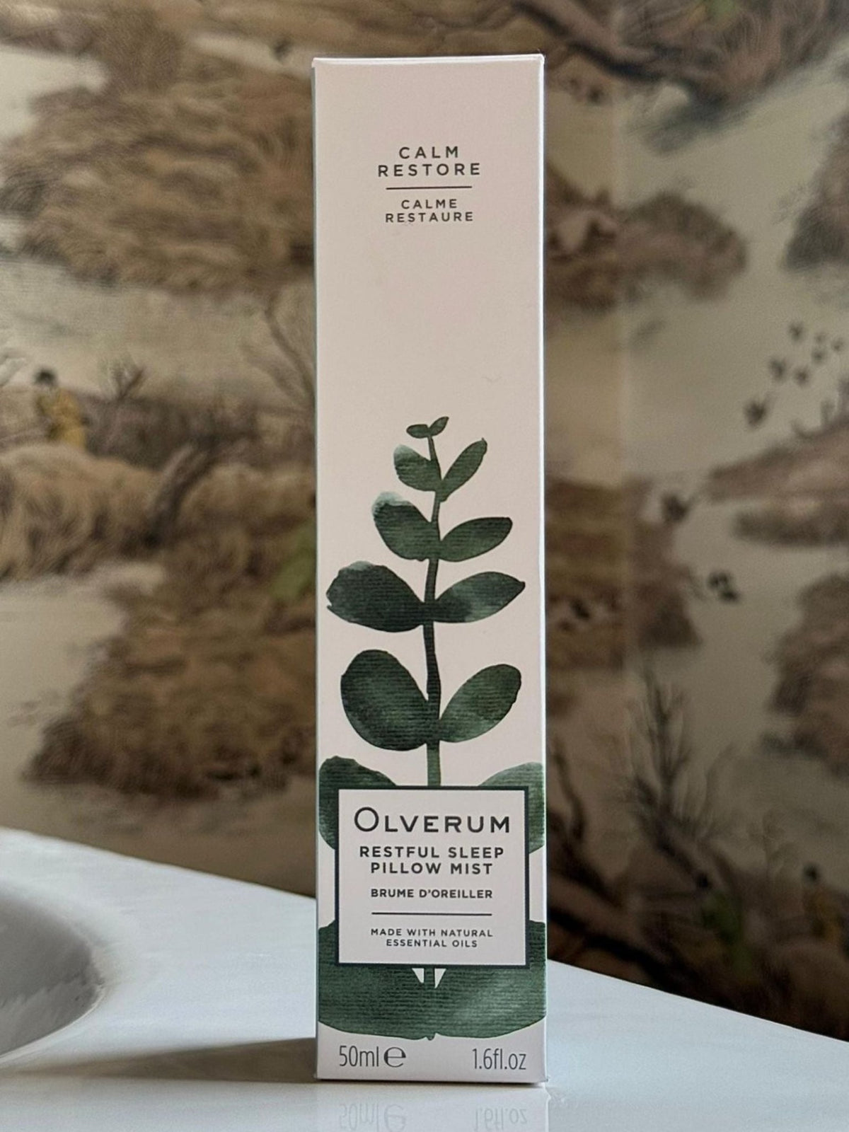 A rectangular box of Olverum Restful Sleep Pillow Mist 30ml, featuring a green eucalyptus-style sprig graphic and text noting it is made with natural essential oils.