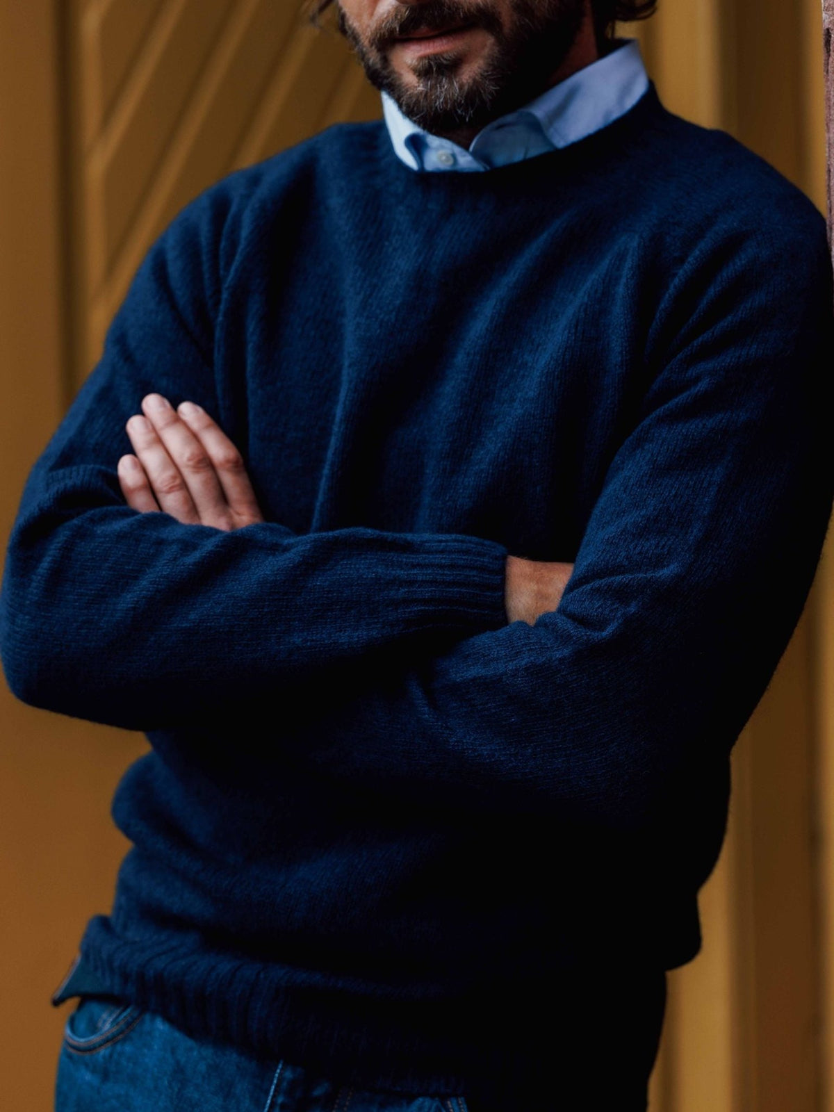 A man with a beard, arms crossed, wearing a blue Campbell’s of Beauly Shetland Jumper over a light blue collared shirt.