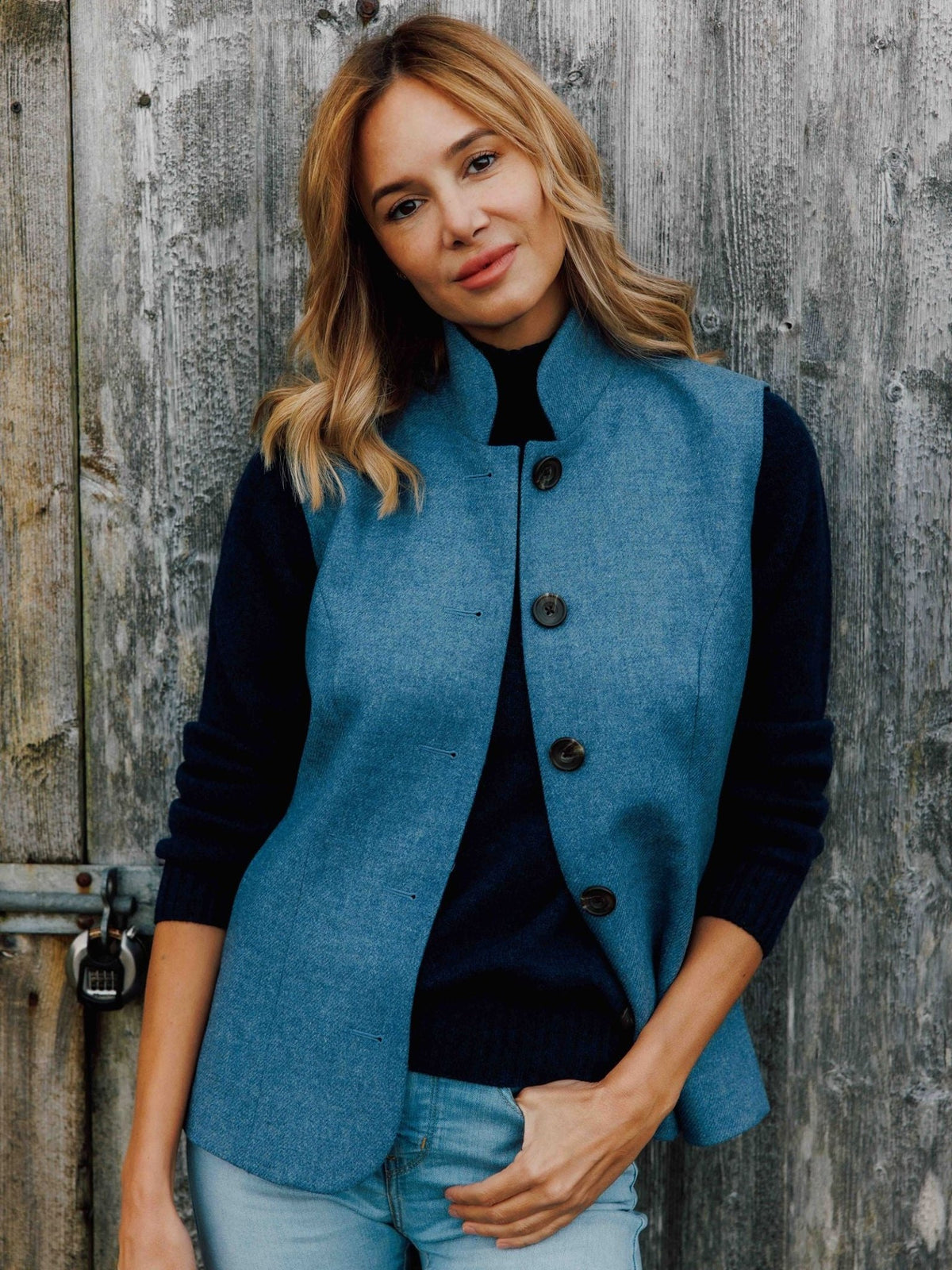 A woman wears a Campbell’s of Beauly Tweed Nehru gilet with a high collar over a dark long-sleeved sweater.