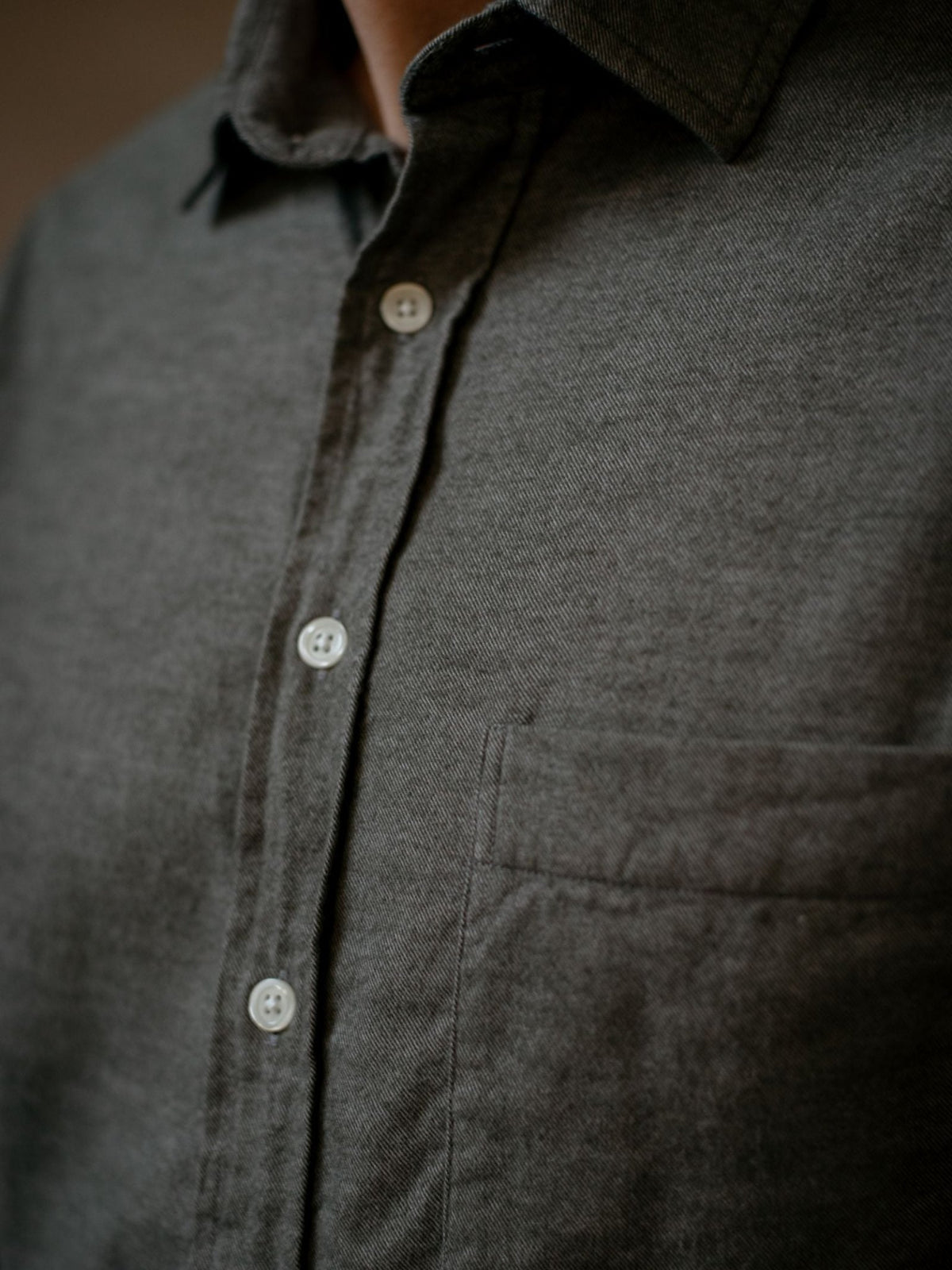 Close-up of a person wearing the Campbell’s of Beauly Twill Shirt in a dark, classic fit, featuring white buttons and a chest pocket. The face is not visible.