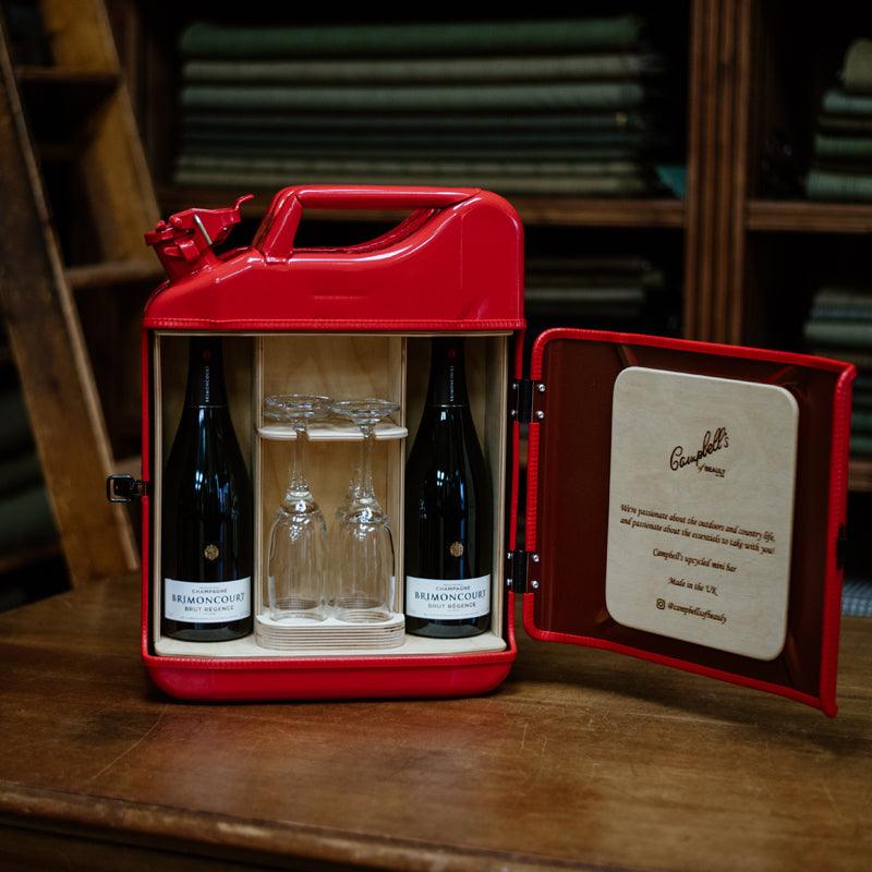 The Brimoncourt Champagne Upcycled Mini Bar by Campbells of Beauly transforms a red Jerry can into a stylish mini bar, with space for two bottles and glasses, a wooden section, and engraved door—perfect for any wine lover.